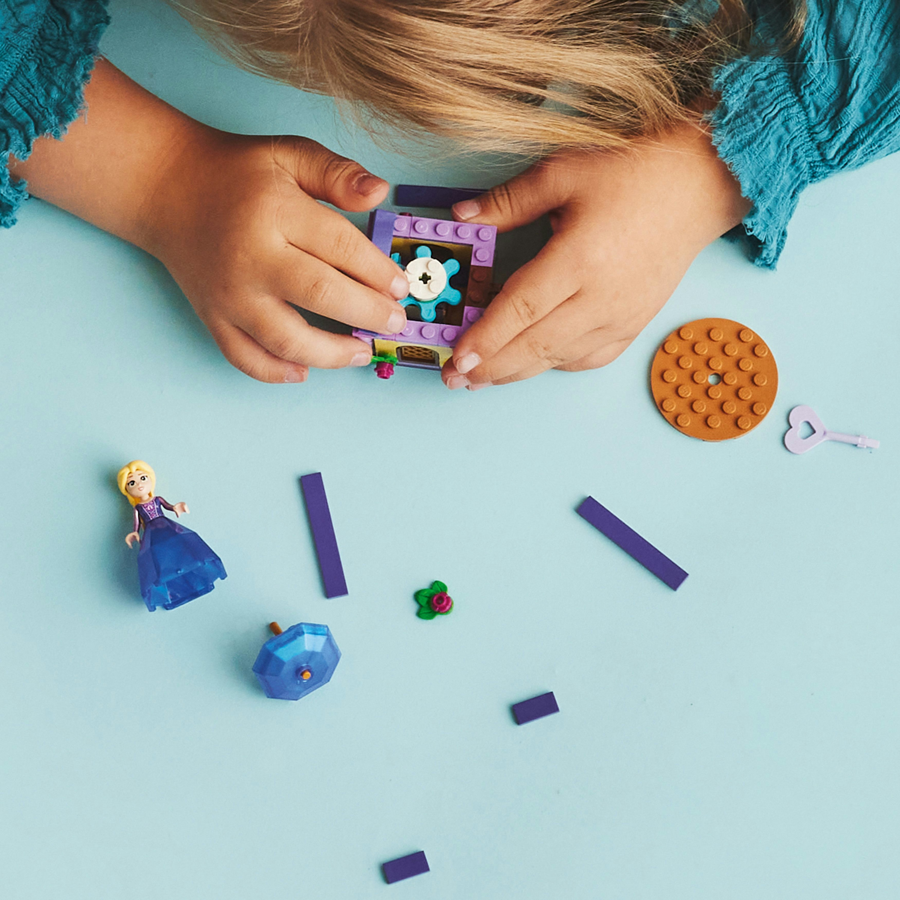 Lego-Teile verstreut auf einer blauen Oberfläche. Enthält eine Mini-Figur, eine Truhe und andere Teile.