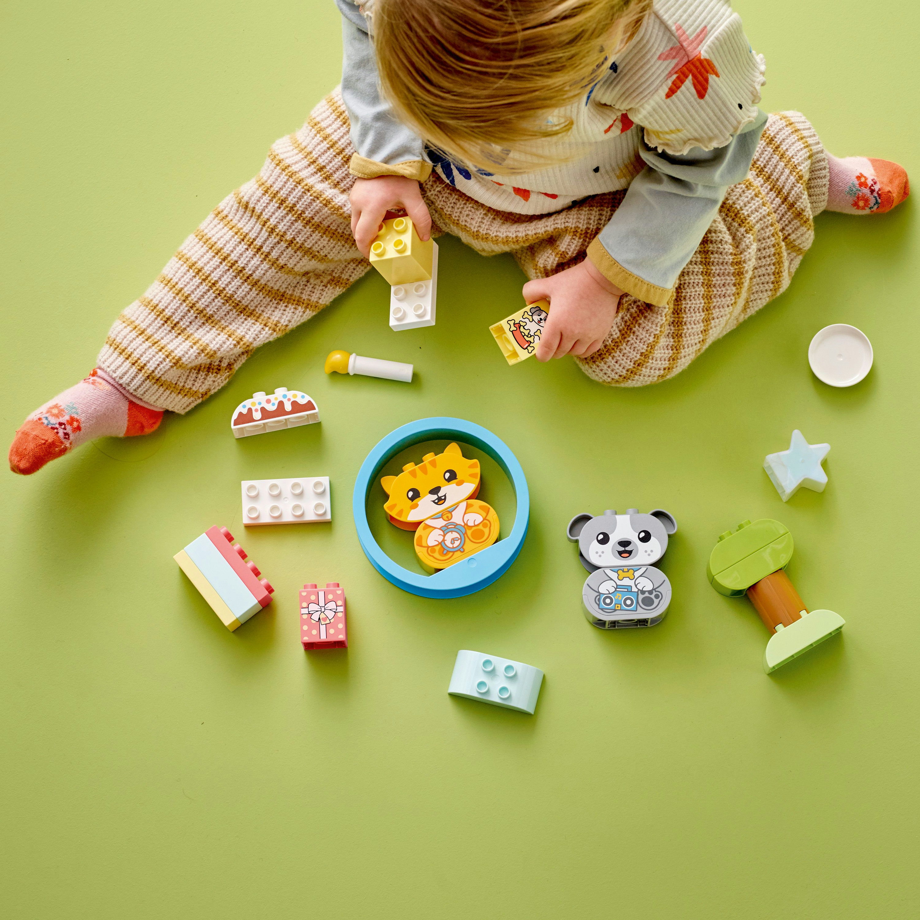 Een kind speelt met Lego Duplo blokken. Er zijn verschillende dierenfiguren en andere kleurrijke blokken.
