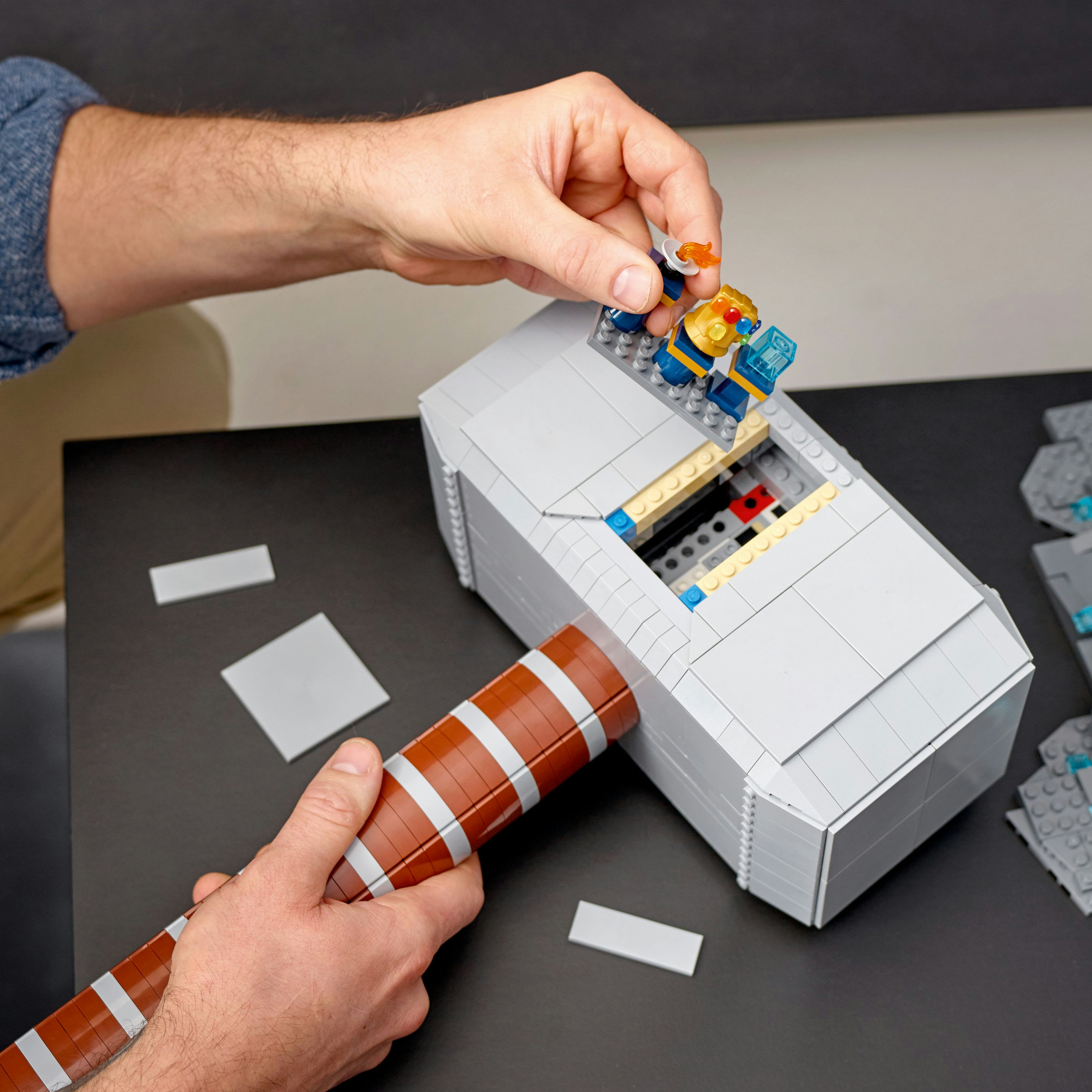 Eller, figürlerle bir Lego Thor çekici topluyor.