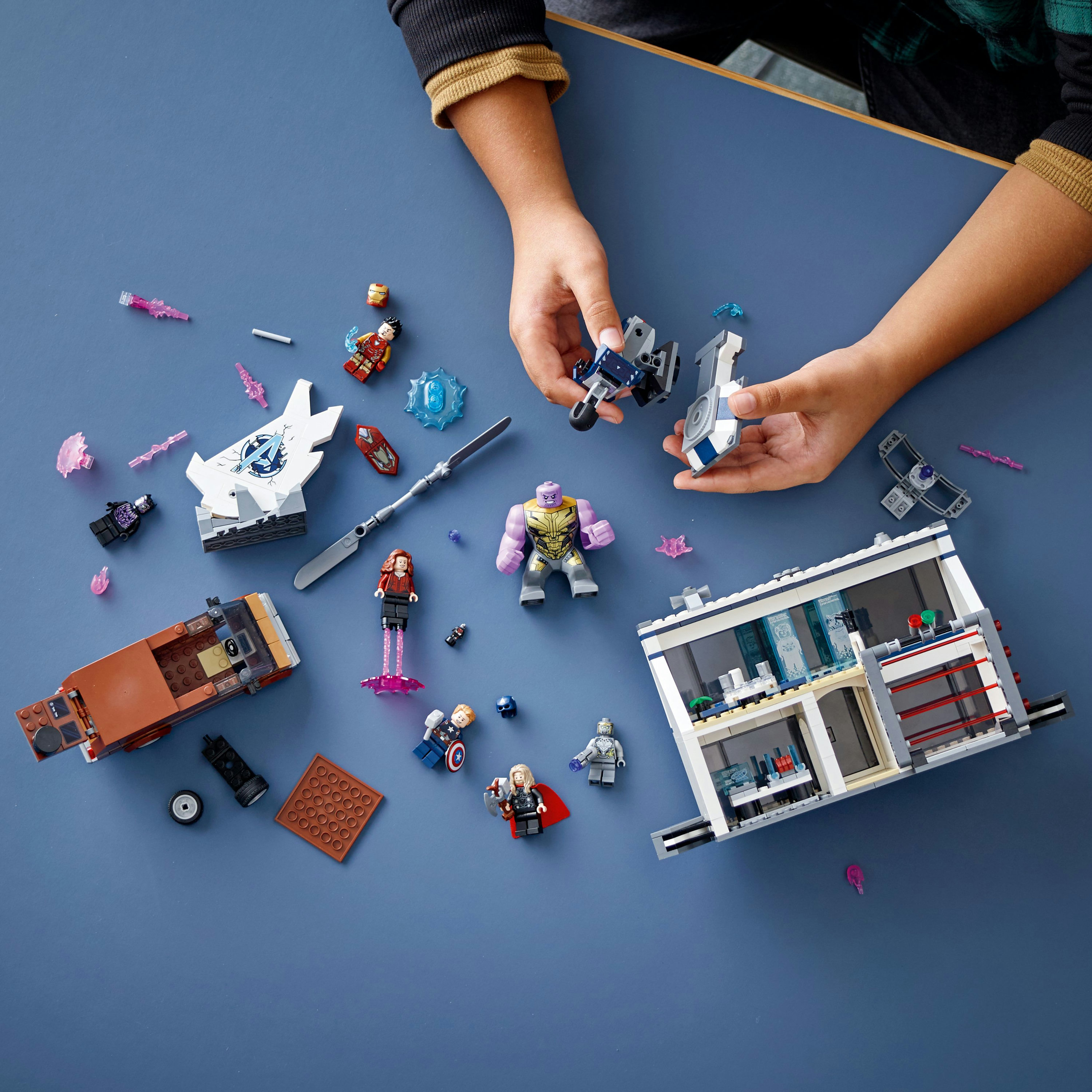 Set Lego con personaggi, tra cui Thanos. Pezzi del set su una superficie blu. Scena di costruzione.