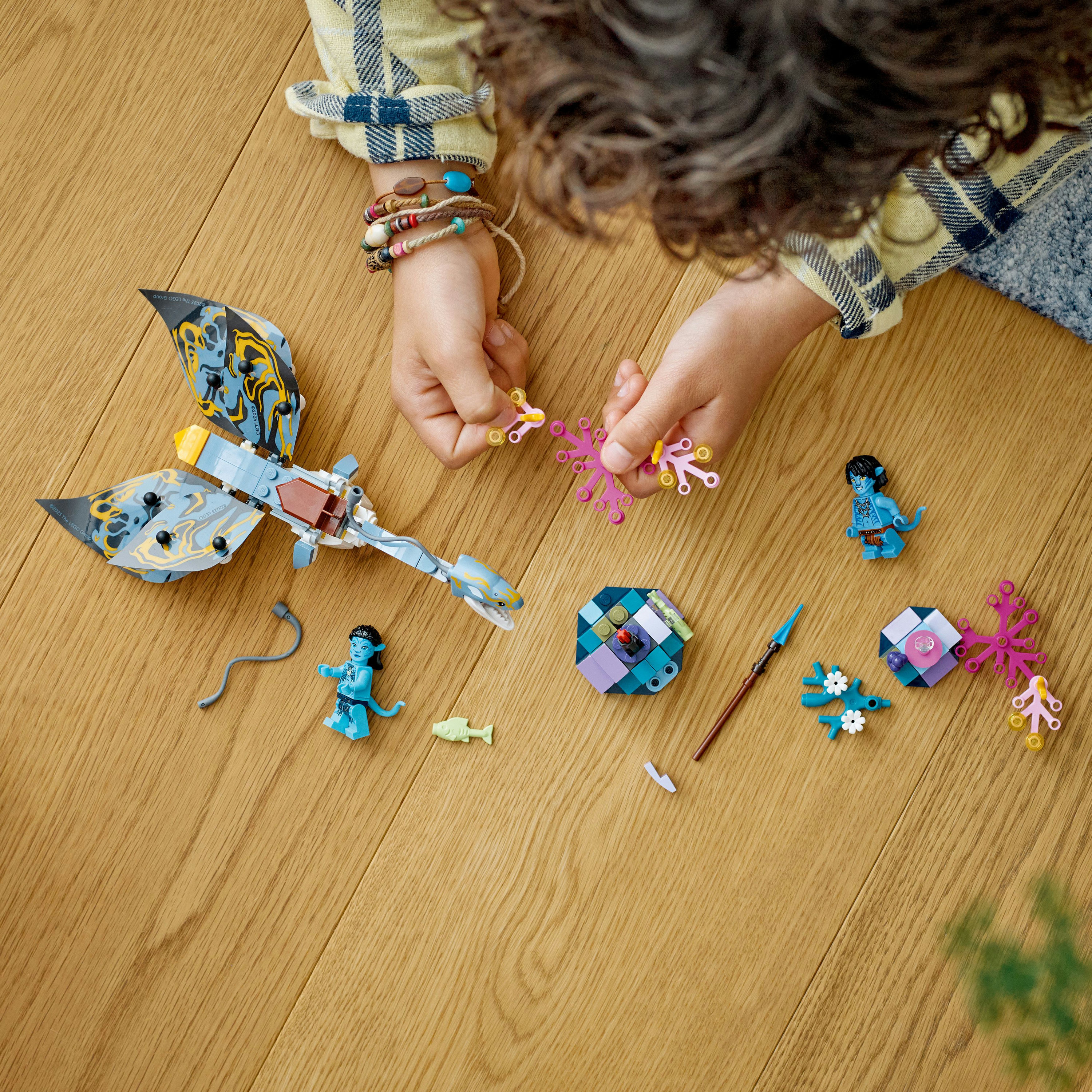 Ein Kind, das ein Lego Avatar-Set mit Figuren und bunten Elementen zusammenbaut.