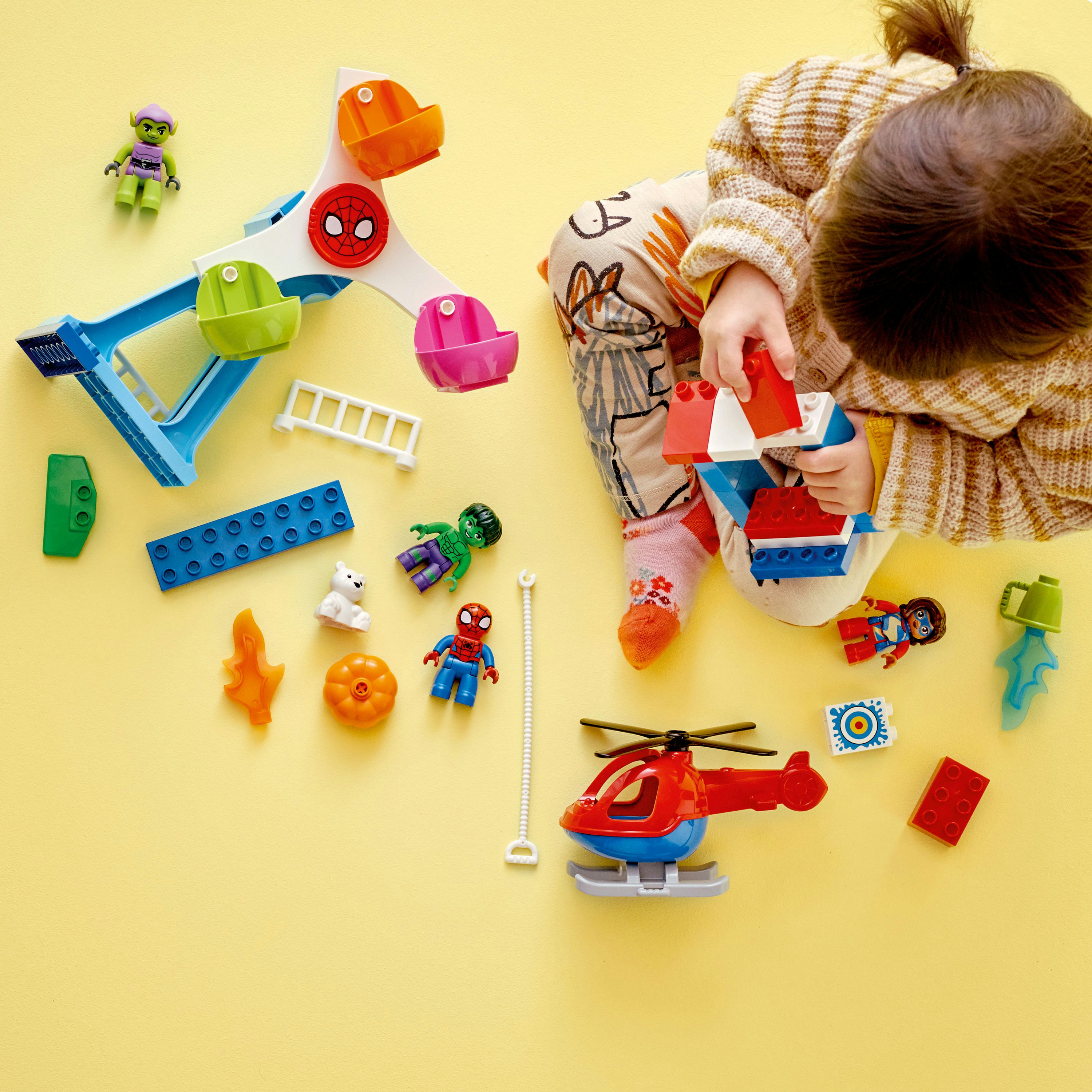 Ein Kind spielt mit einem Lego Duplo Set mit einem Riesenrad, Spiderman und anderen Figuren.