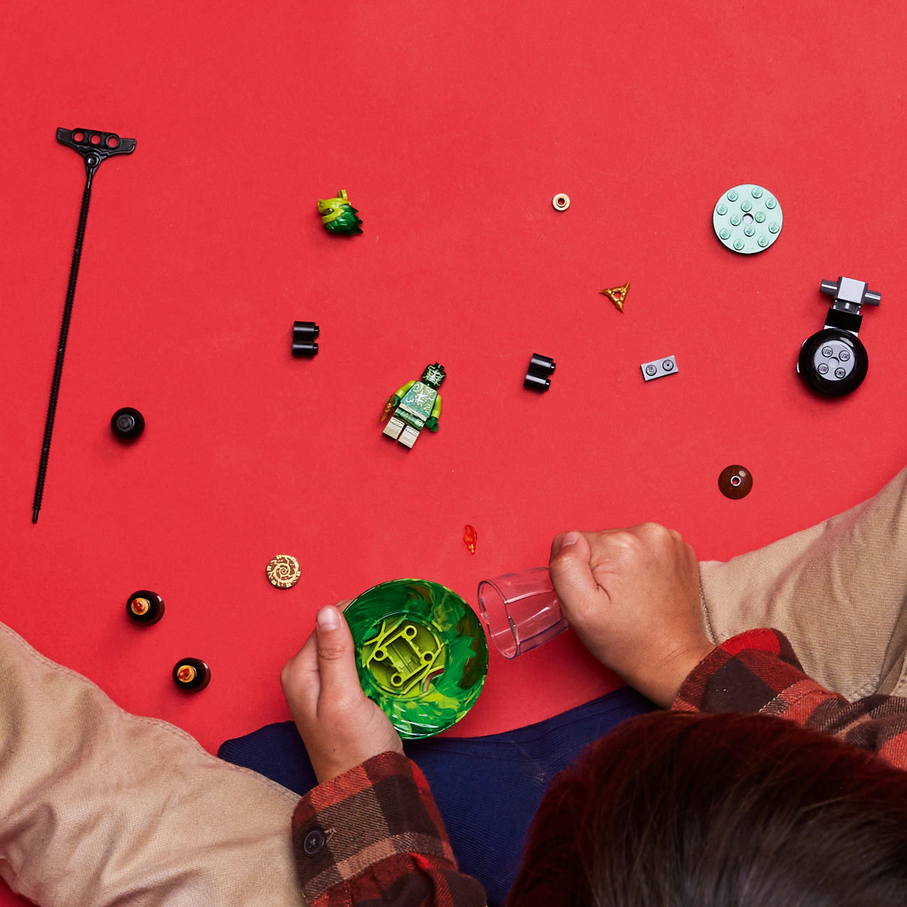 Mains et pièces Lego éparpillées sur fond rouge.