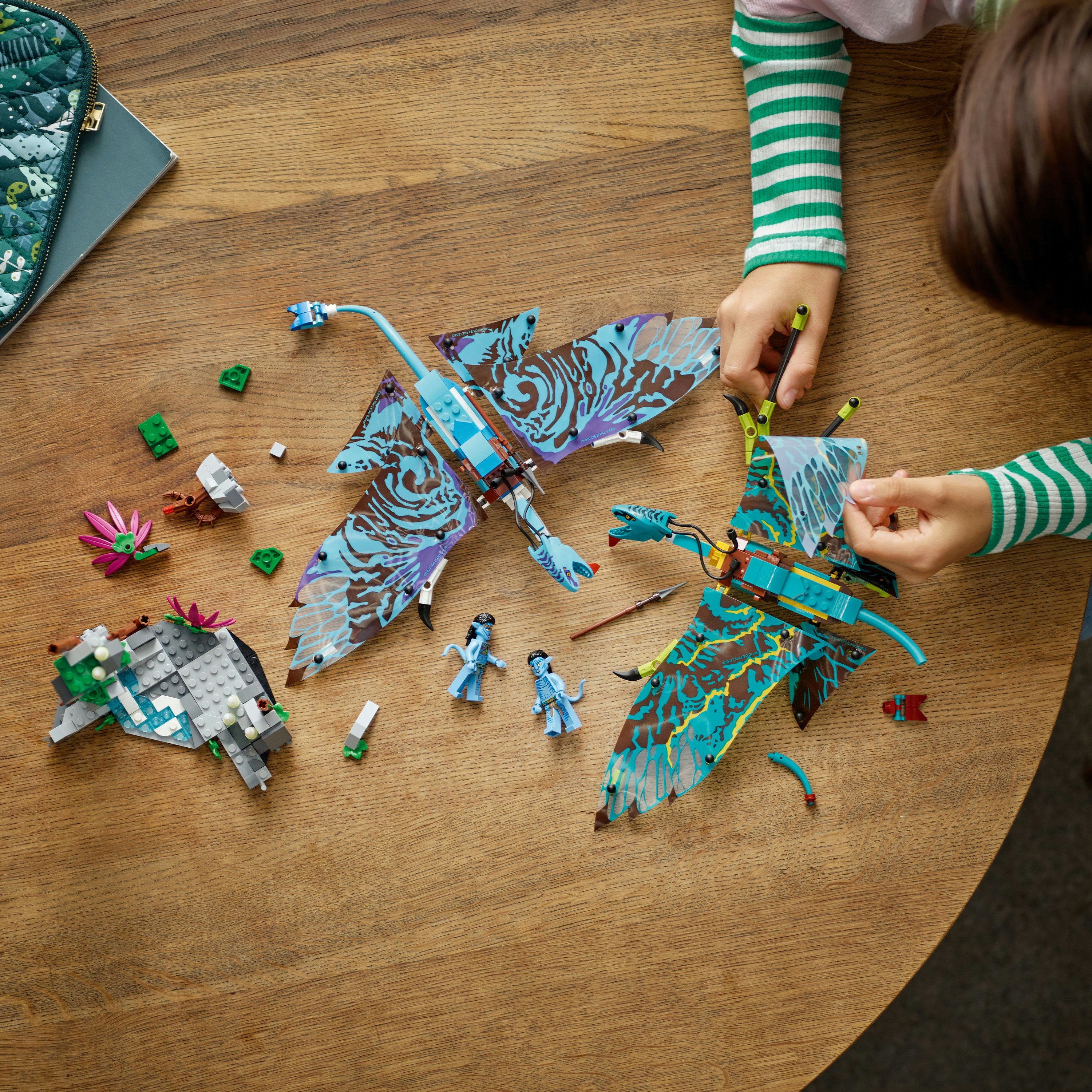 Kinder spielen mit Lego Avatar Sets auf einem Holztisch, mit Na'vi Figuren und Kreaturen.
