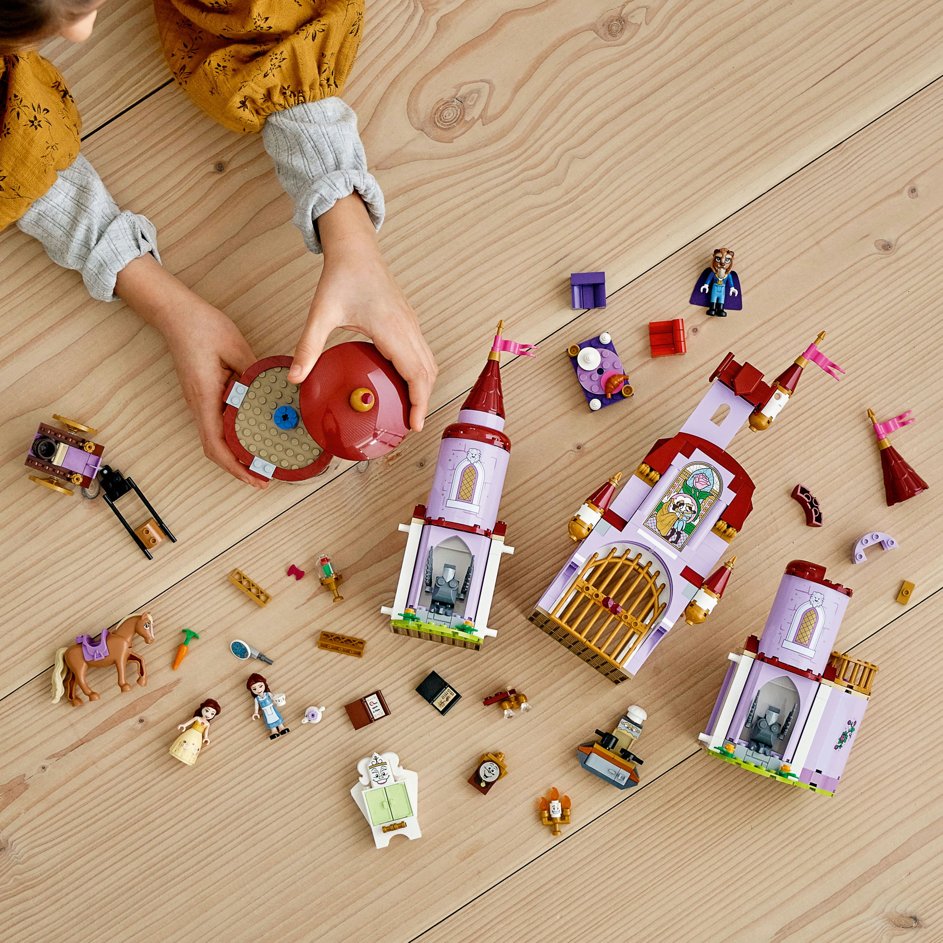Un bambino interagisce con un set LEGO Disney Princess, assemblando elementi del castello su una superficie di legno.