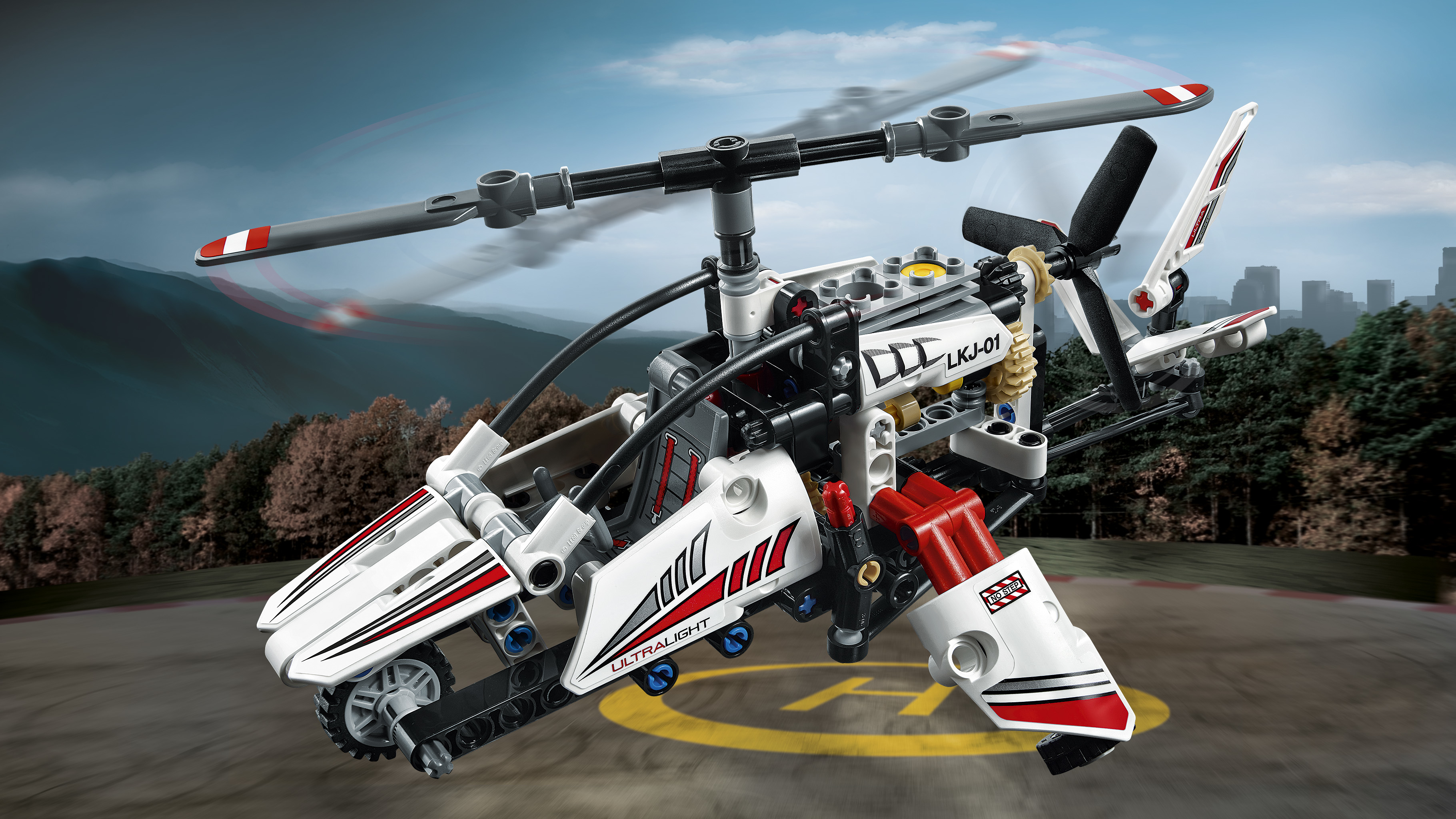 Biało-czerwony helikopter Lego z wirującymi łopatami na rozmytym tle miasta.