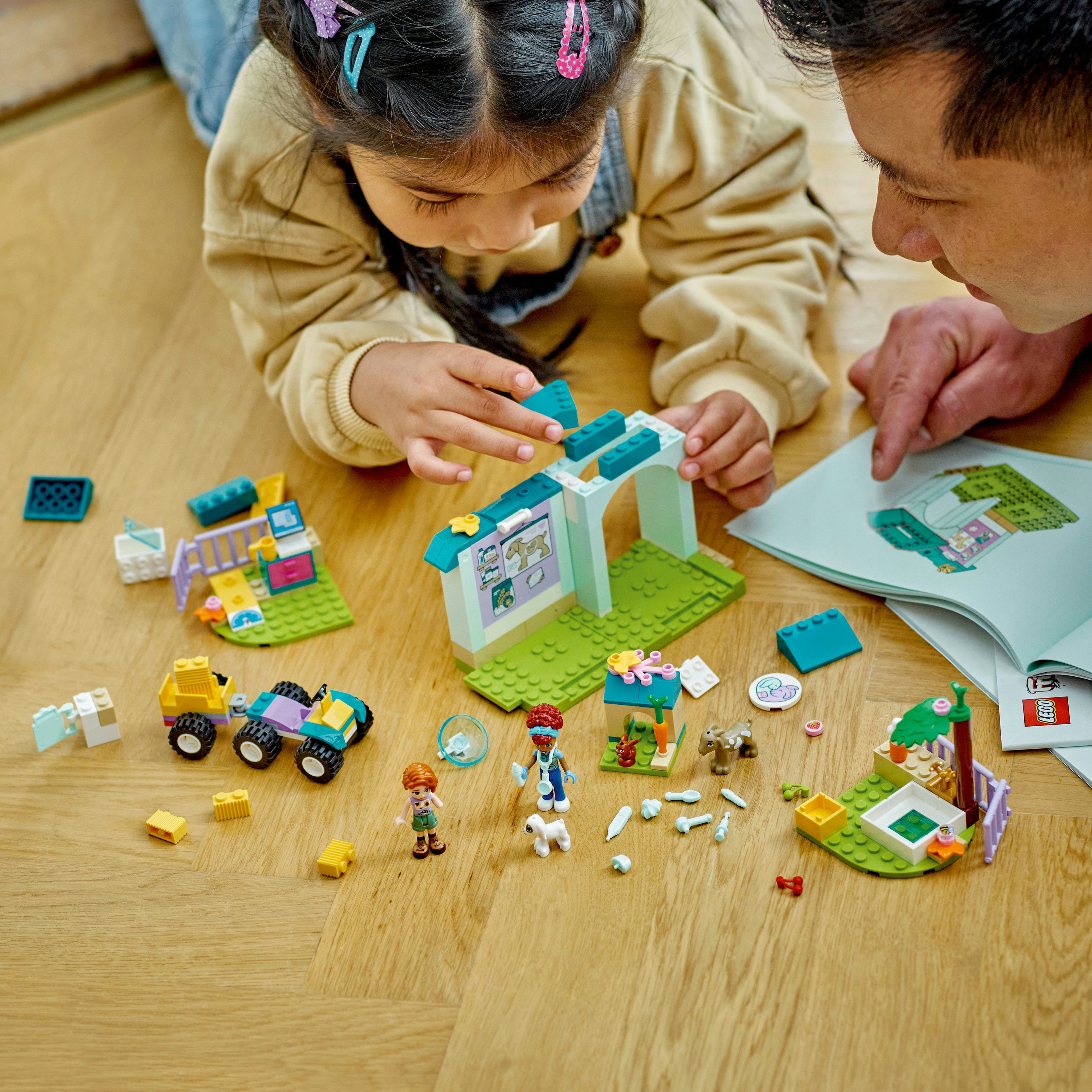 Bir çocuk ve bir adam, ahşap bir zeminde hayvan figürlü bir Lego setiyle oynuyor. Bir kılavuz mevcut.