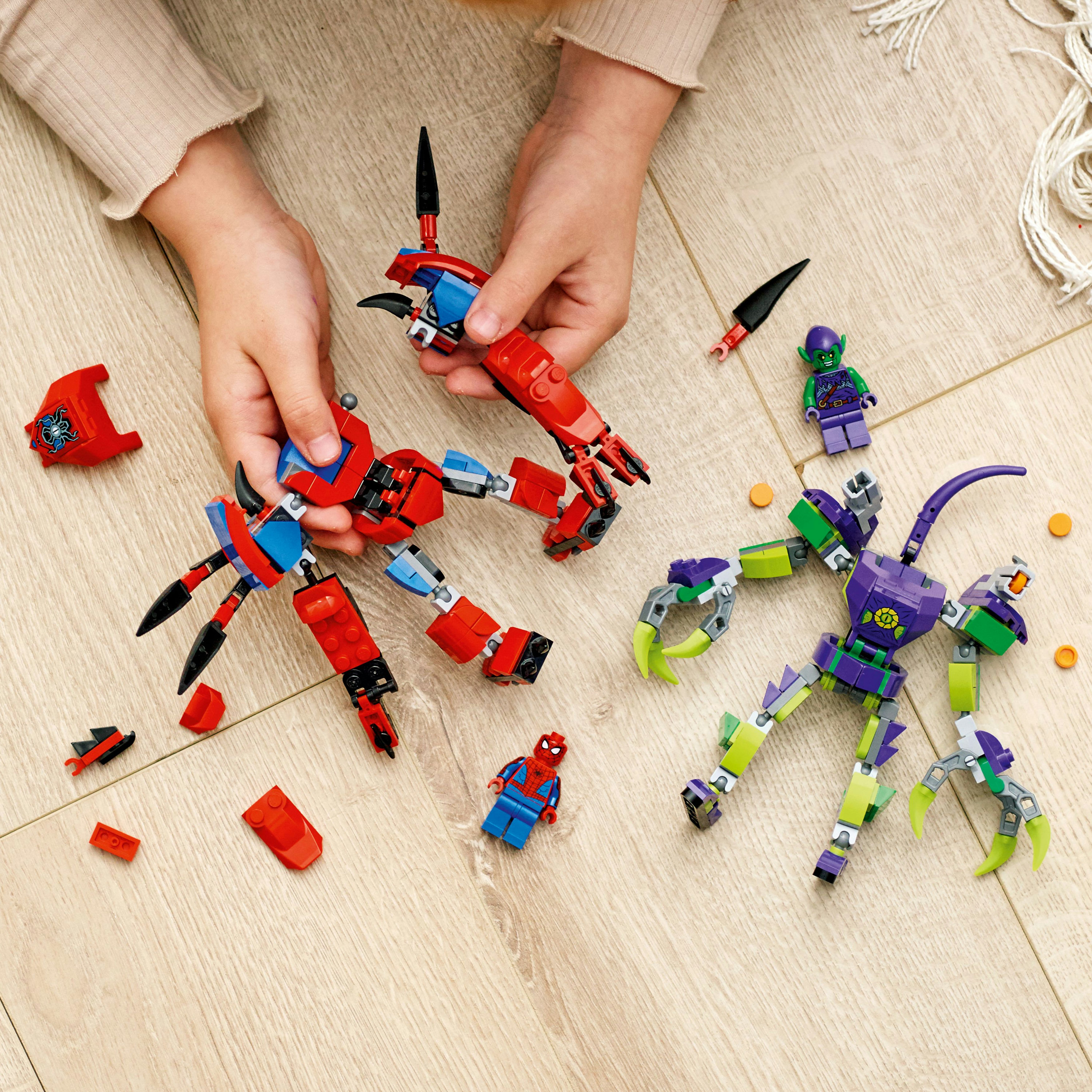 Bir çocuk, Örümcek Adam ve Goblin mech'leri inşa ederek Lego Örümcek Adam setleriyle oynuyor.
