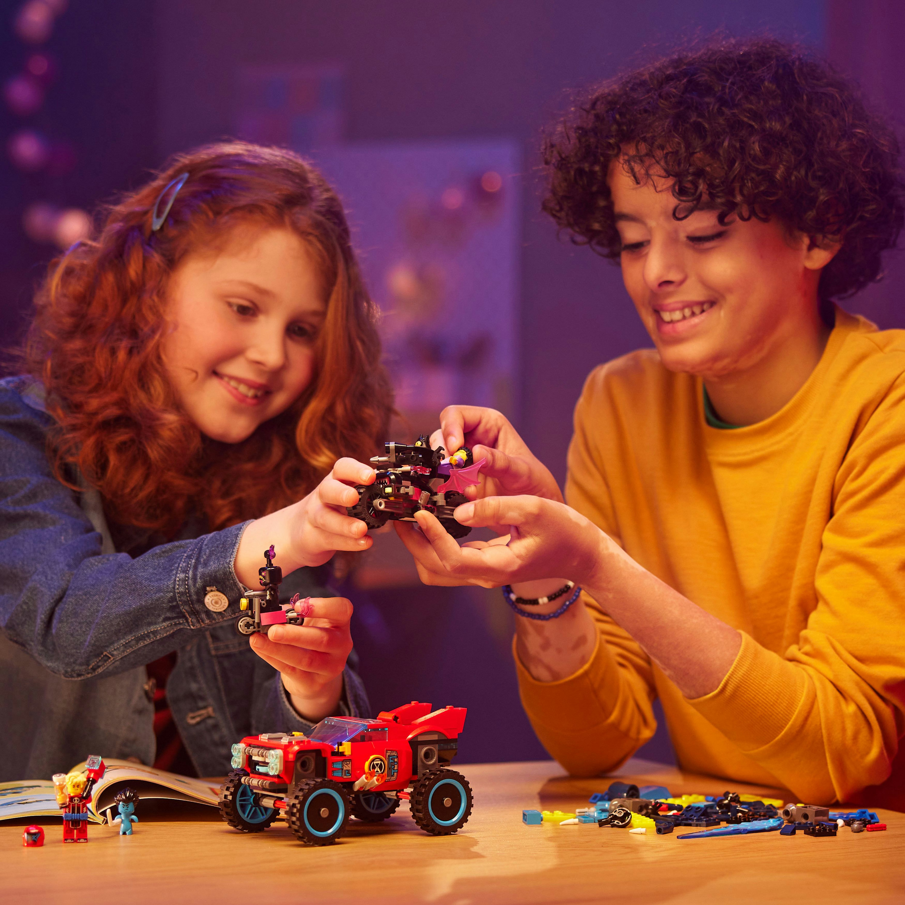 Due bambini giocano con i set Lego. Uno tiene in mano un monster truck rosso. L'altro un piccolo giocattolo.