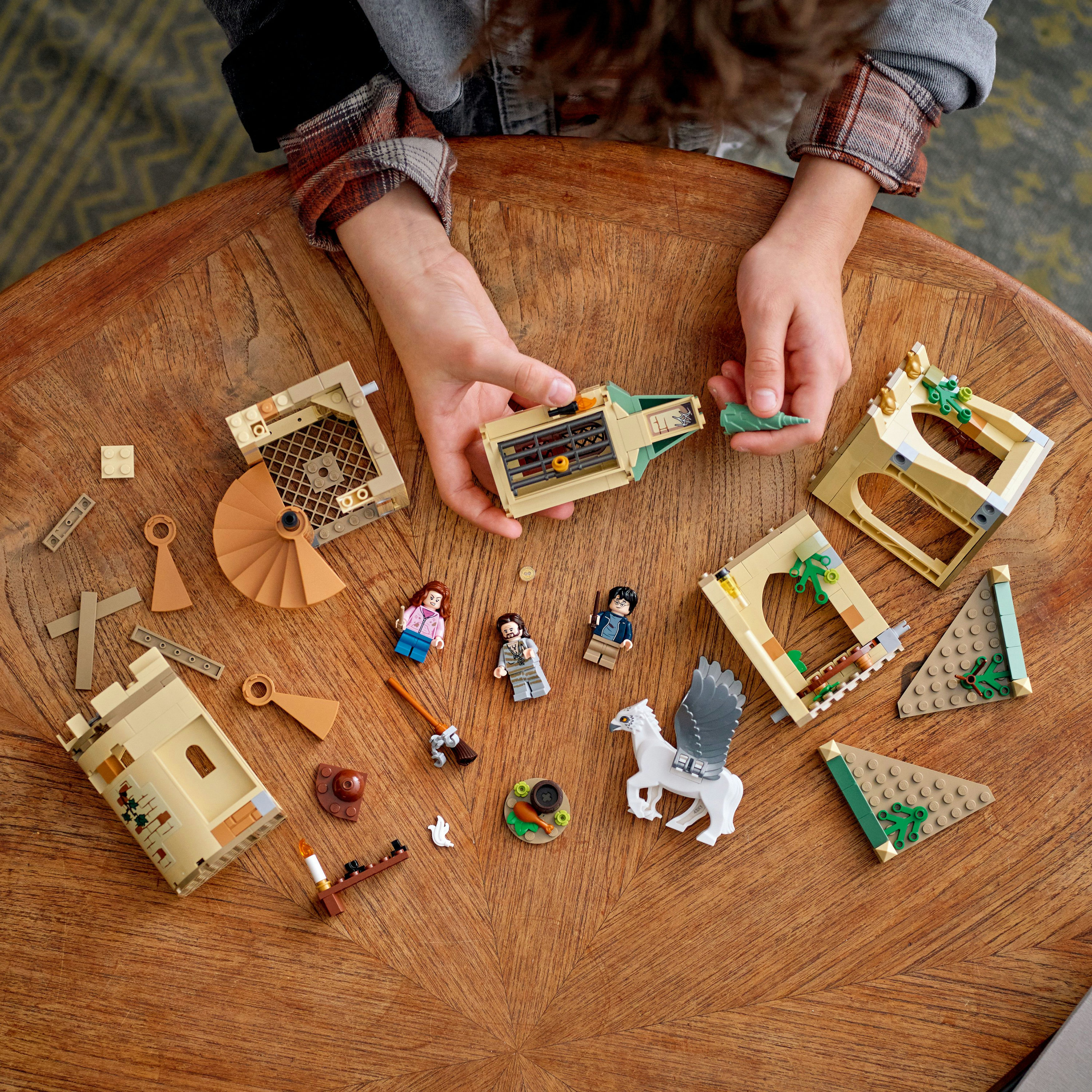 Een kind rangschikt Harry Potter LEGO-stukken op een houten tafel, waaronder minifiguren en bouwcomponenten.
