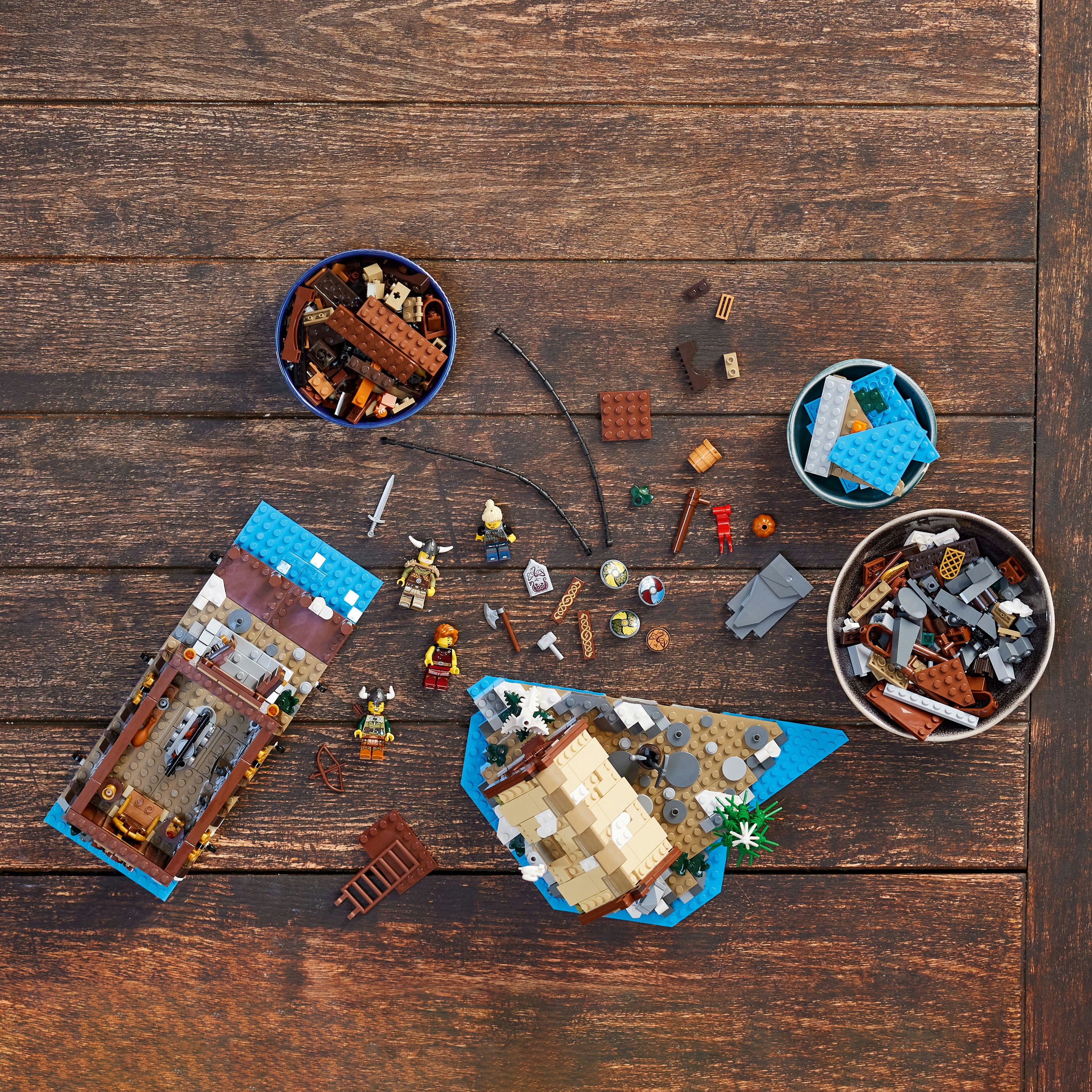 Zestaw Lego ze stołem drewnianym i różnymi elementami, w tym łodziami, figurkami i akcesoriami.