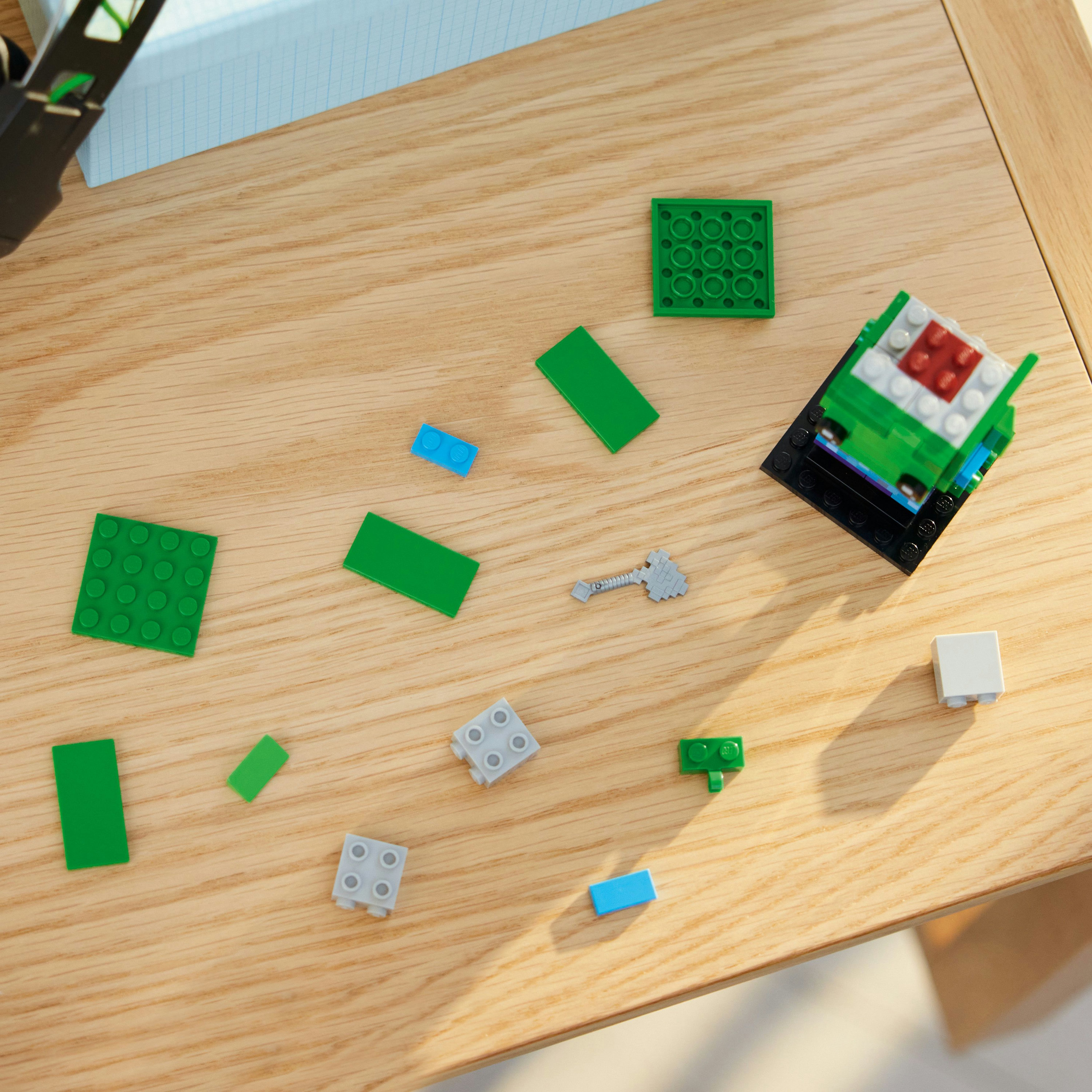 Verschiedene Lego-Teile und eine teilweise zusammengebaute grüne Lego-Struktur auf einem Holztisch.