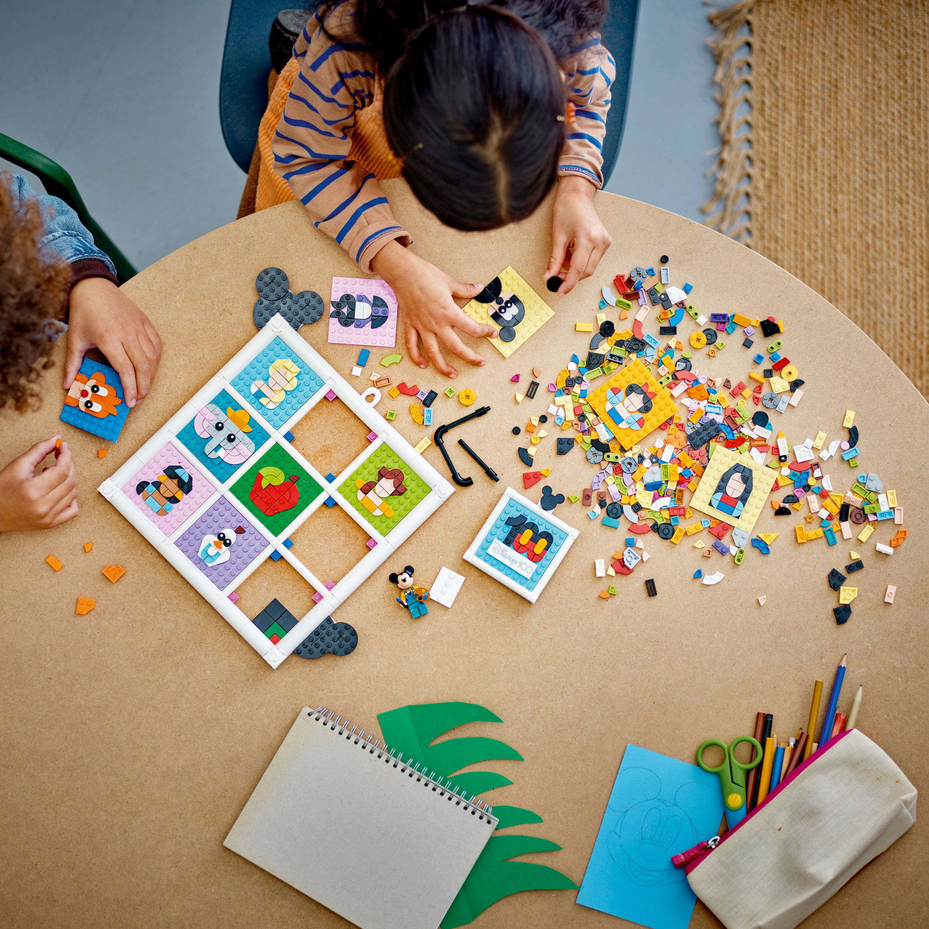 Dwoje dzieci bawi się klockami Lego. Siedzą przy stole.