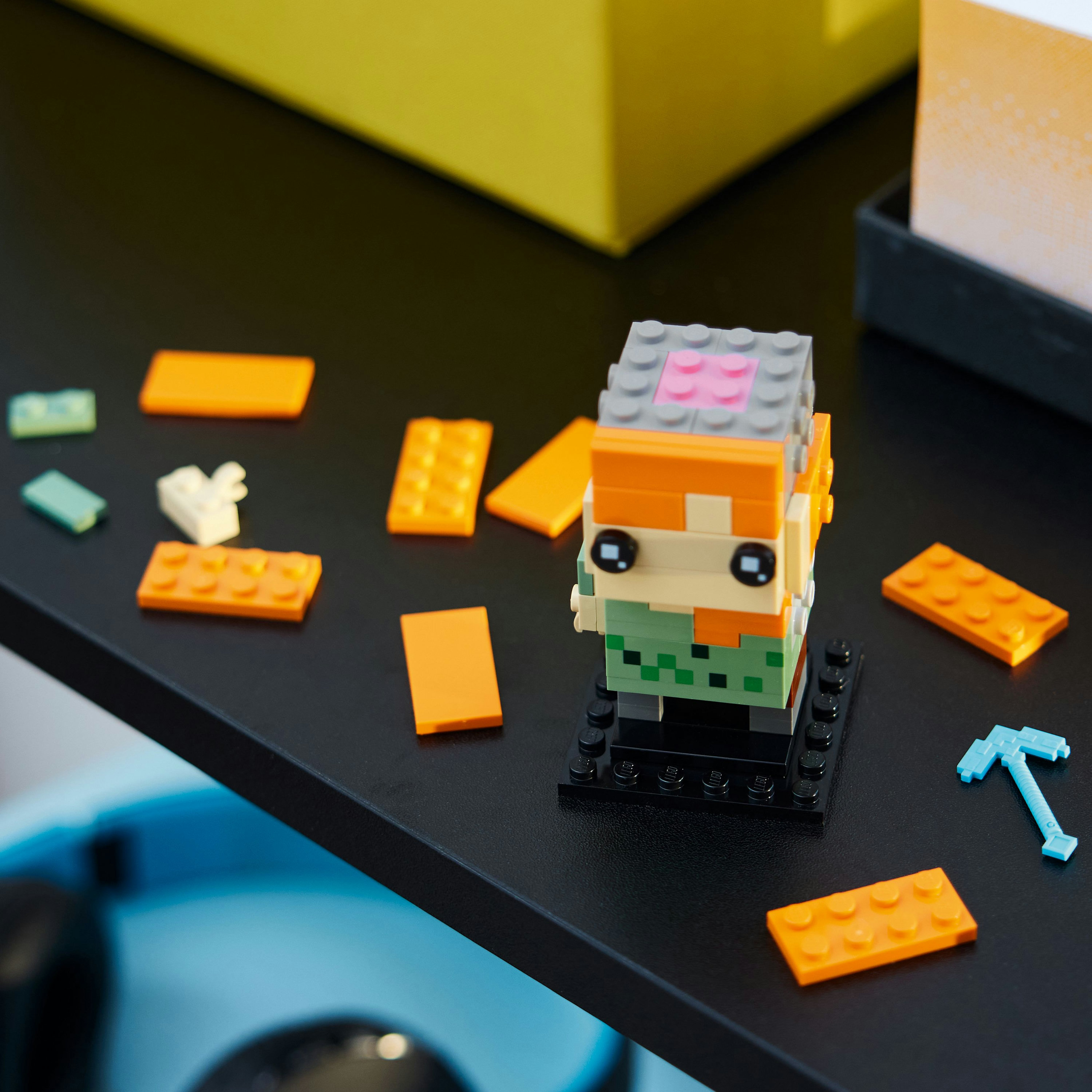Lego Minecraft Alex figuur, gebouwd met blokken. Oranje, grijze en groene details.