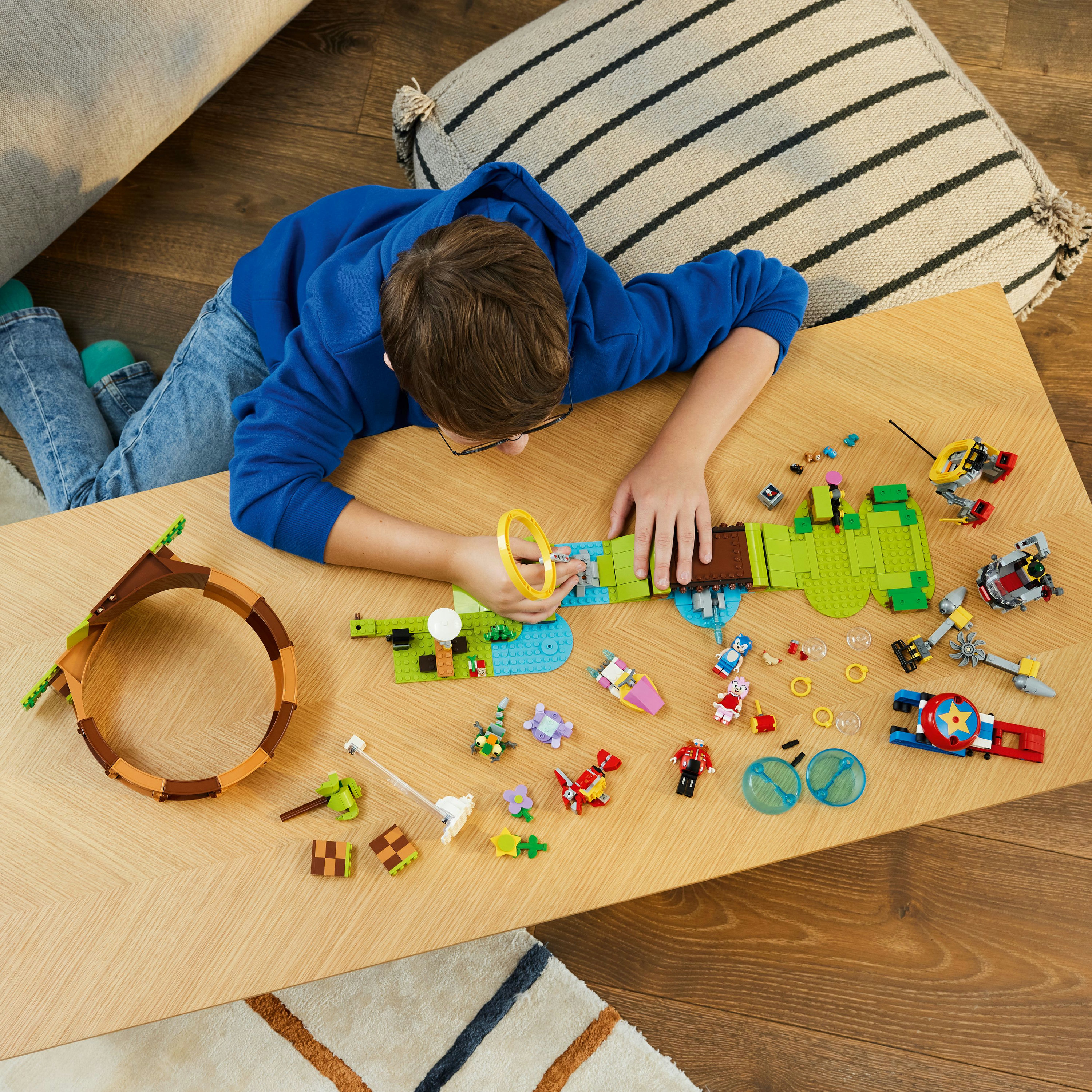 Ein Junge spielt auf einem Tisch mit einem Lego-Set. Es zeigt verschiedene bunte Sonic the Hedgehog Charaktere und Elemente.