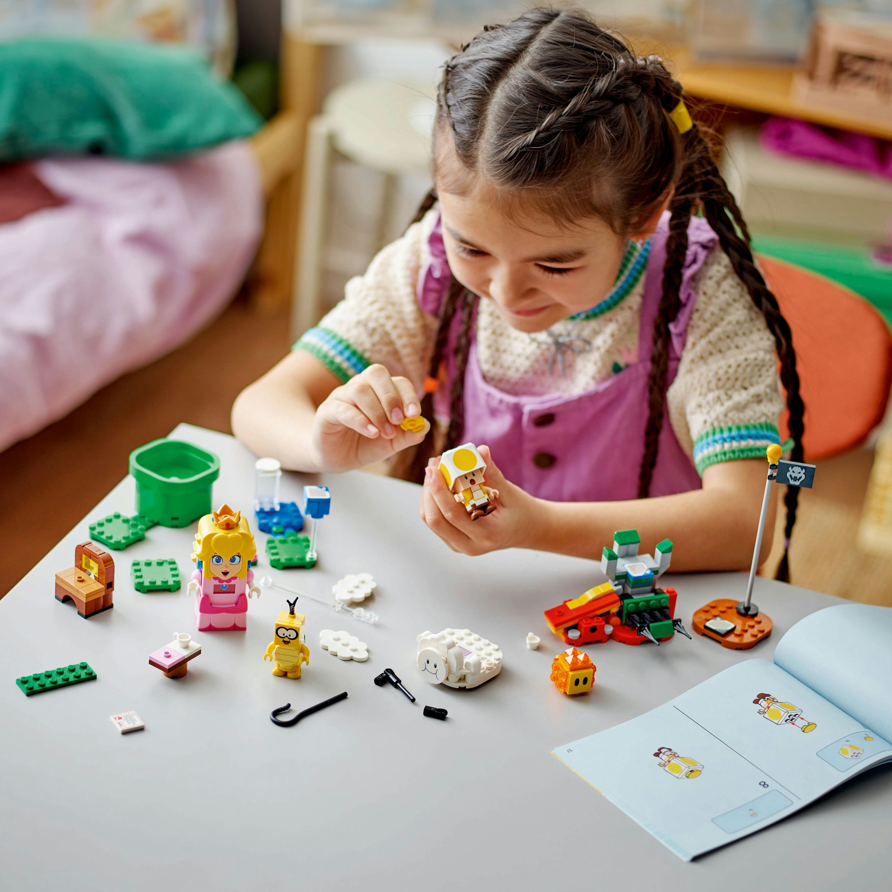 Fille jouant avec Lego : Une fille jouant avec des figurines et accessoires Lego sur une table, vue de dessus.
