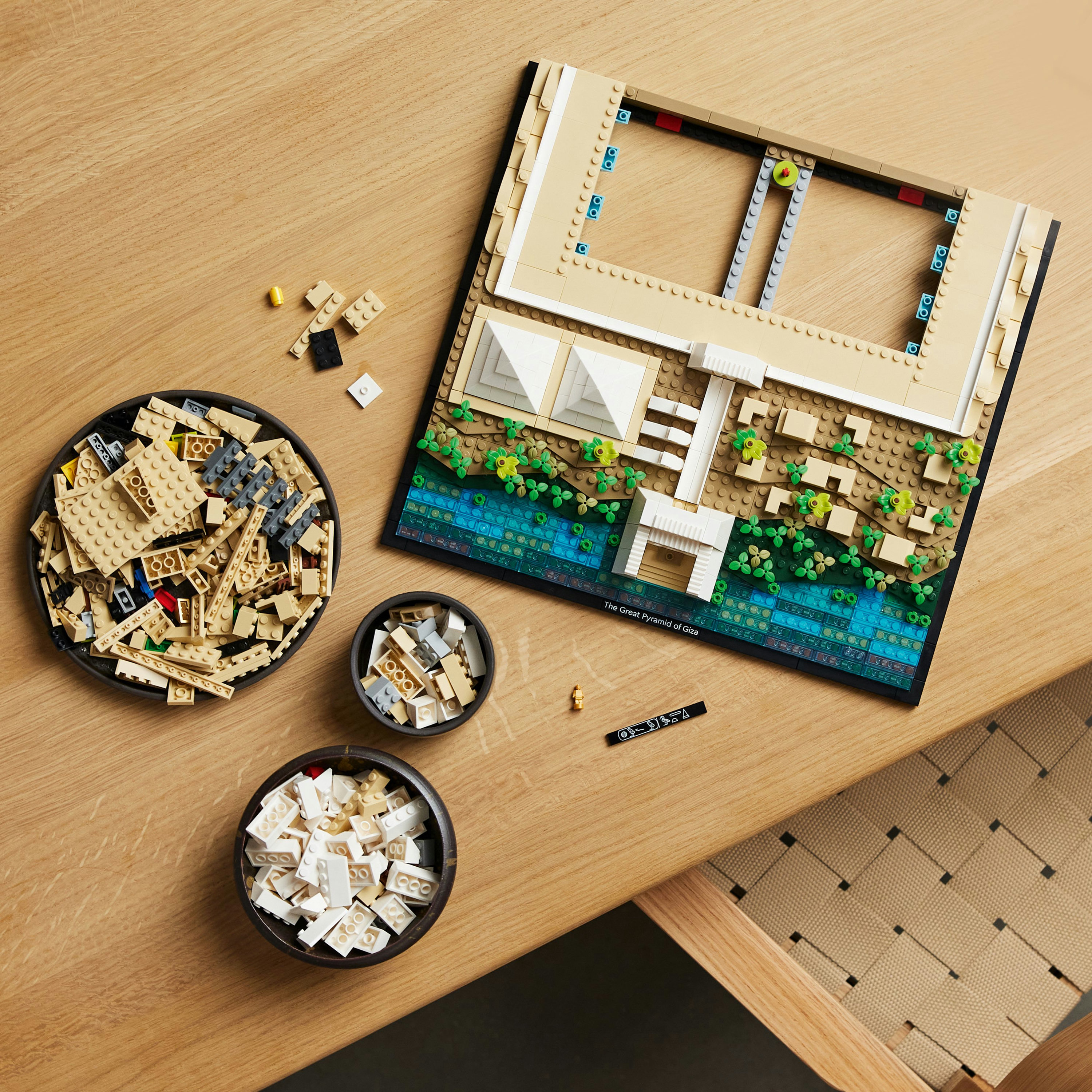 Ein Lego-Set der Großen Pyramide von Gizeh, auf einem Holztisch mit Schalen voller Steine aufgebaut.