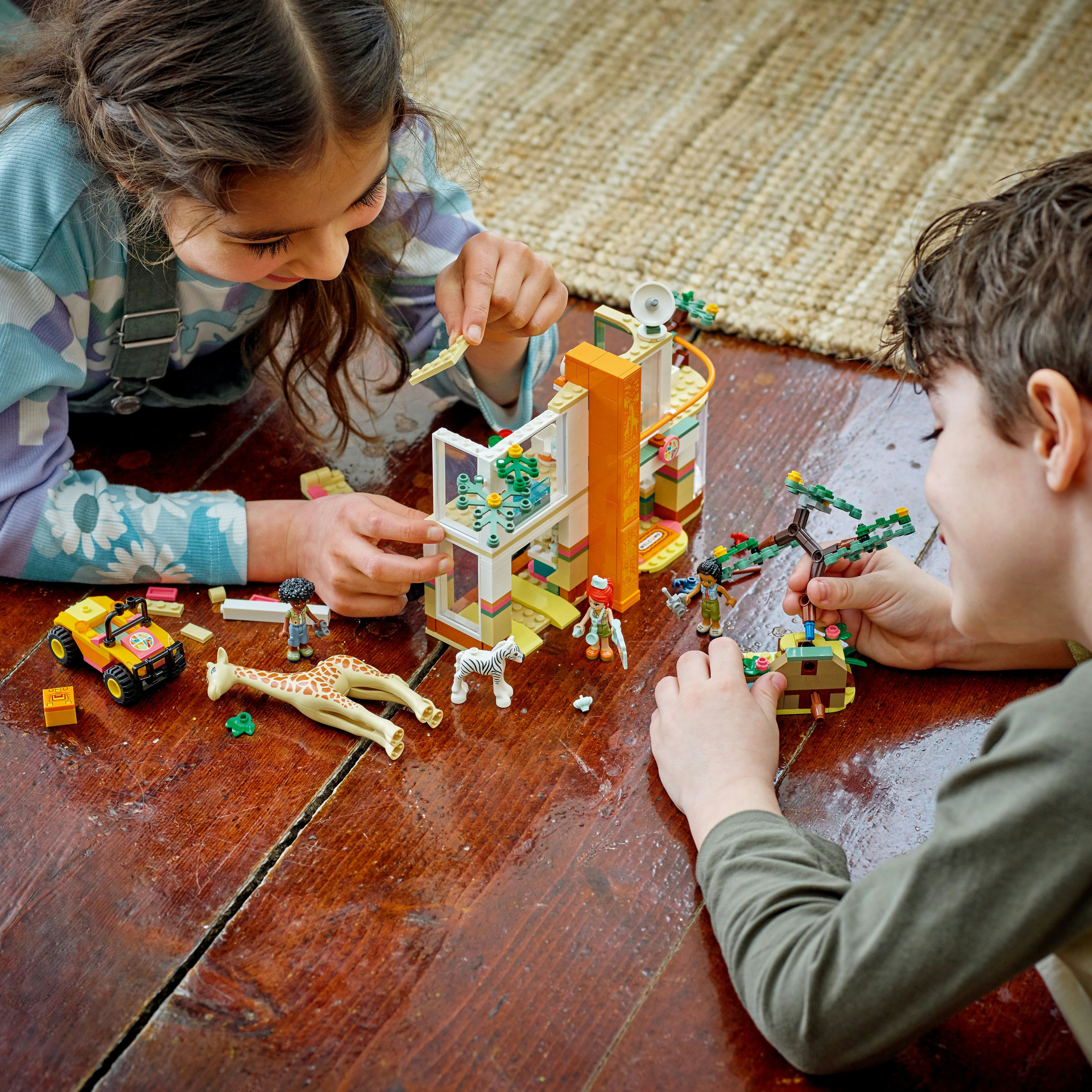 Kinder spielen mit Lego. Eine Giraffe, ein Zebra und ein Gebäude, mit einem Holzboden.
