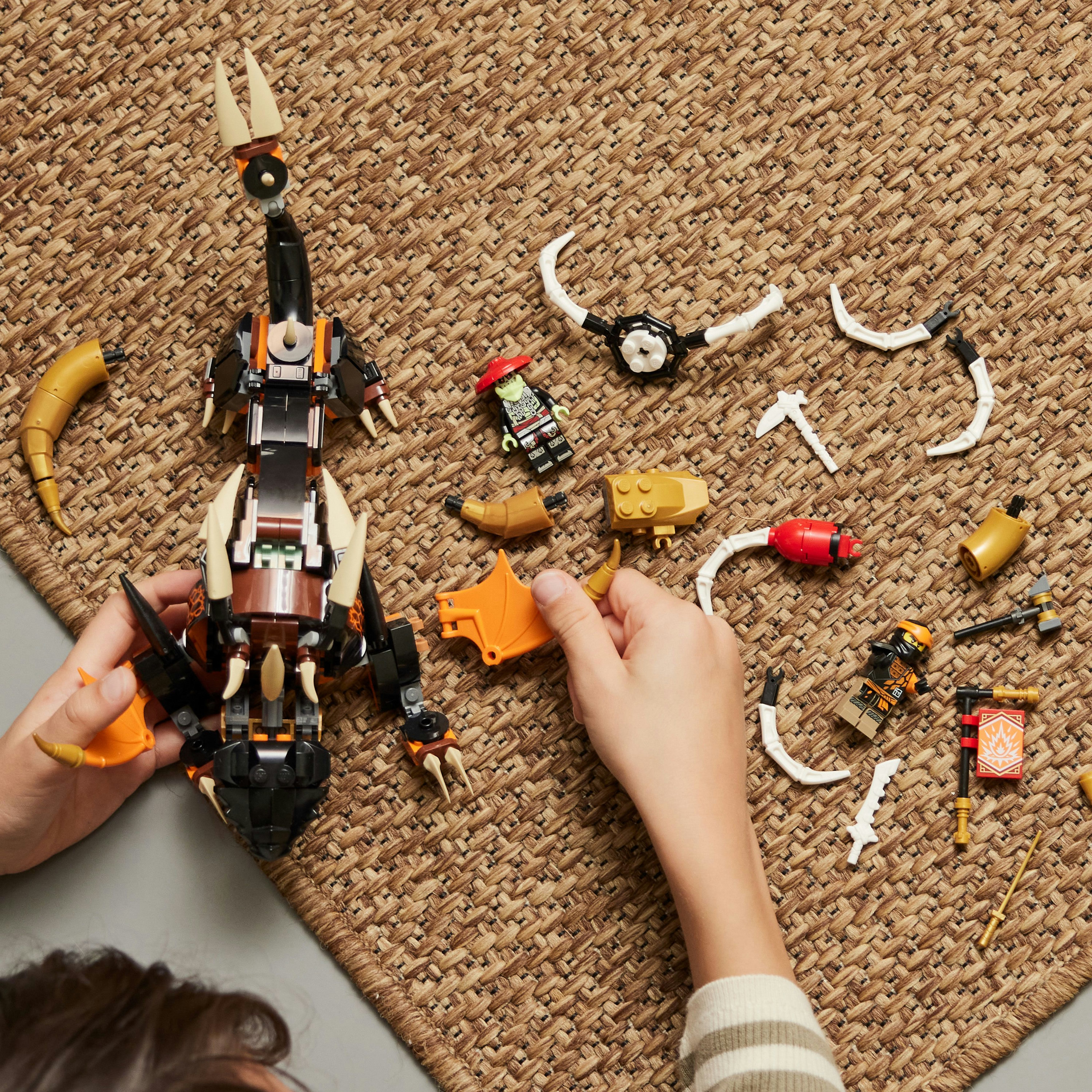 Een persoon monteert een Lego-set met een schorpioenachtig wezen en onderdelen.