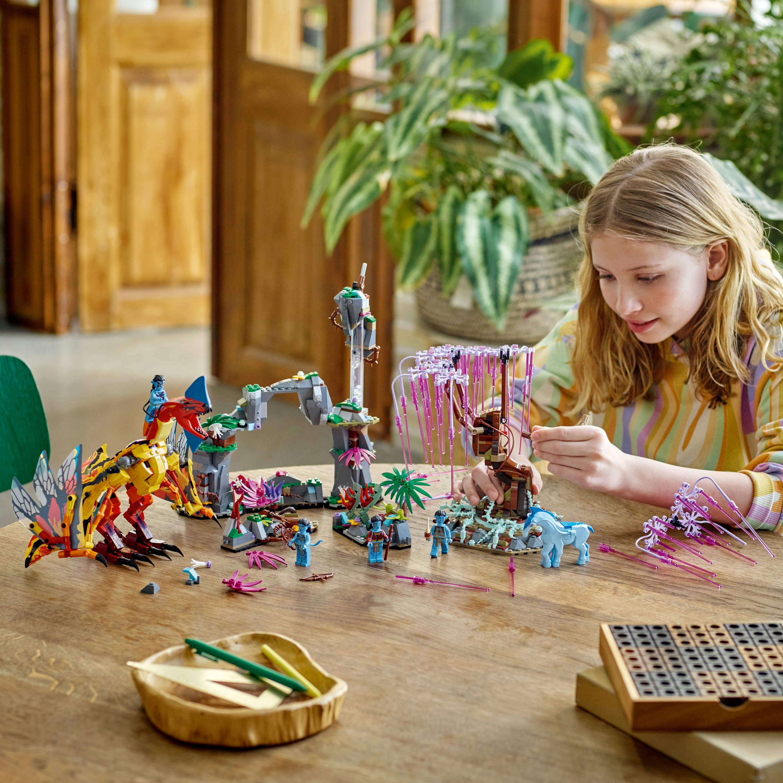 Dziewczynka bawiąca się zestawem Lego Avatar na drewnianym stole. Figurki i stwory.