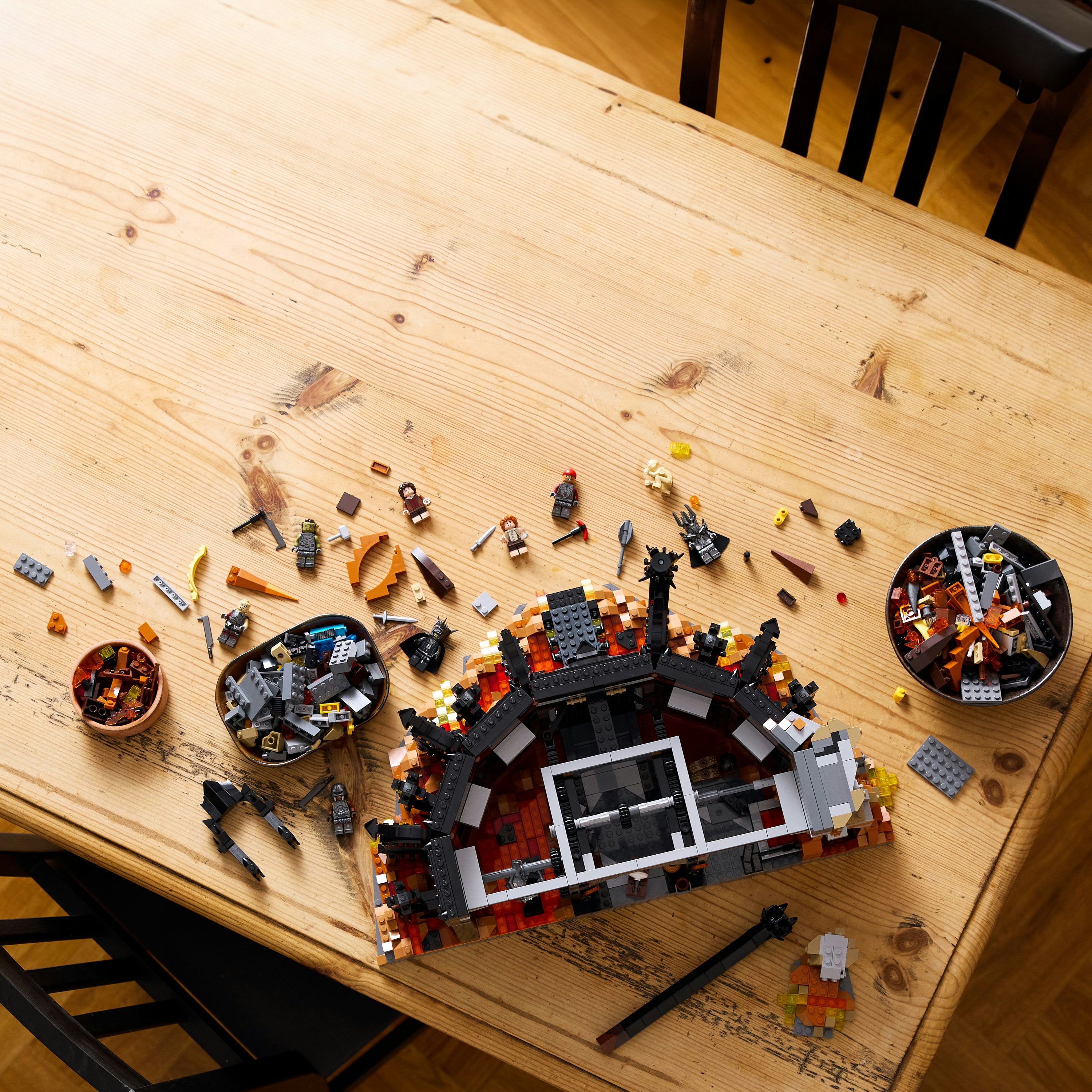 Scena konstrukcji Lego. Drewniany stół z klockami Lego, miskami i częściowo zbudowaną konstrukcją.