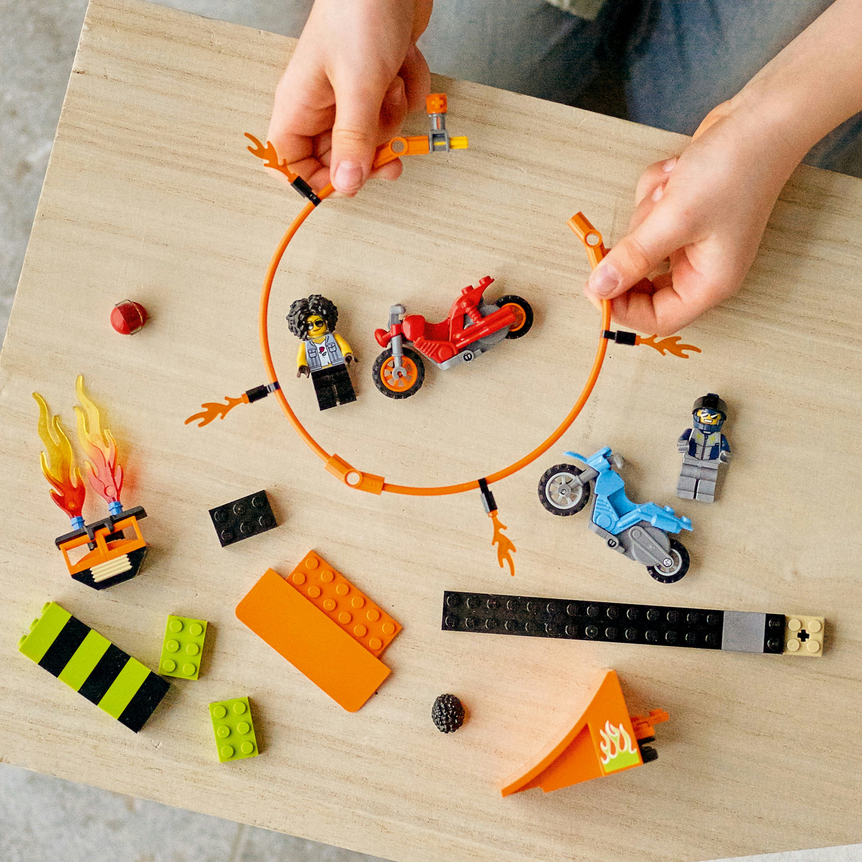 Lego stunt show scene met speelgoed motorfietsen, hellingen en minifiguren.