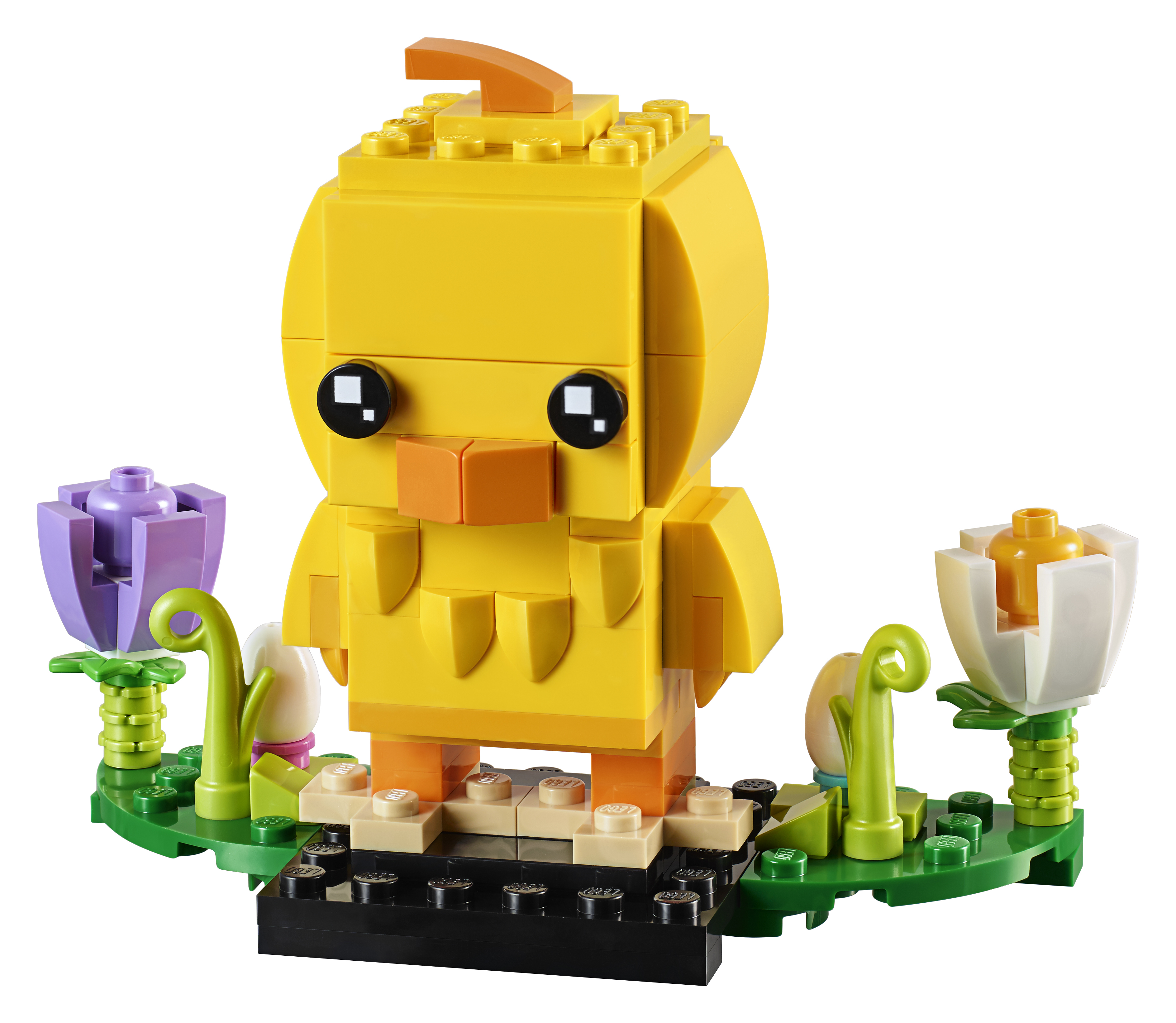 Ein Lego-Küken aus gelben Steinen, das auf grünem Gras mit lila und weißen Lego-Blumen steht.