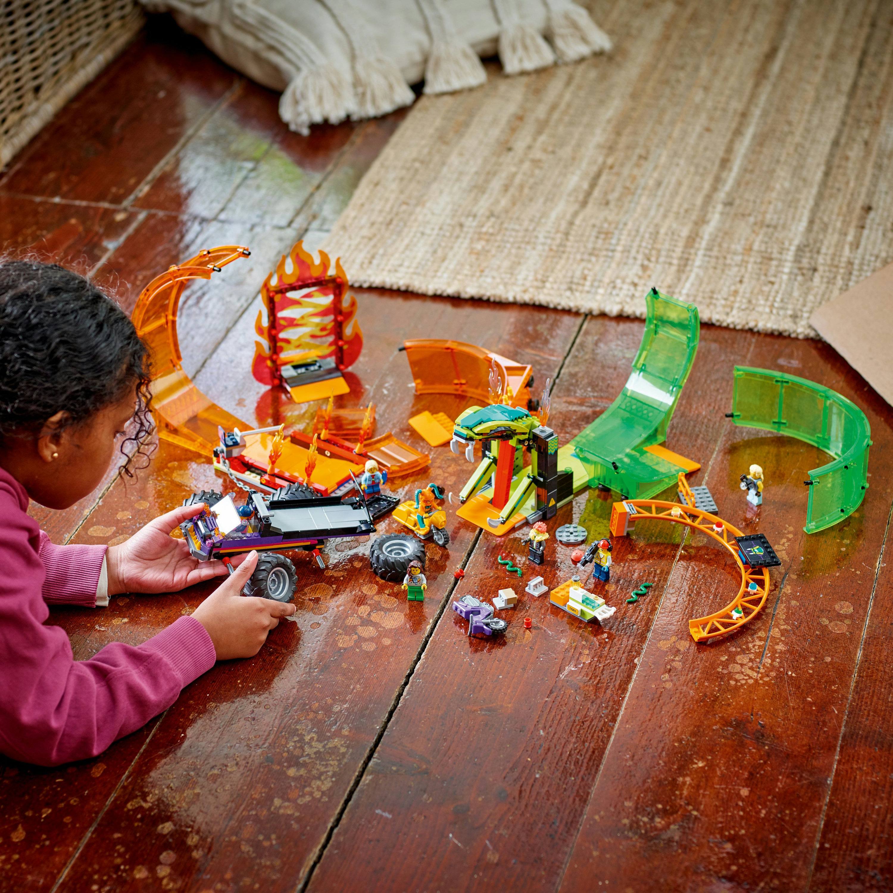 Ein Kind spielt mit einem Lego City Set, mit einer Rennstrecke und verschiedenen Lego-Figuren.