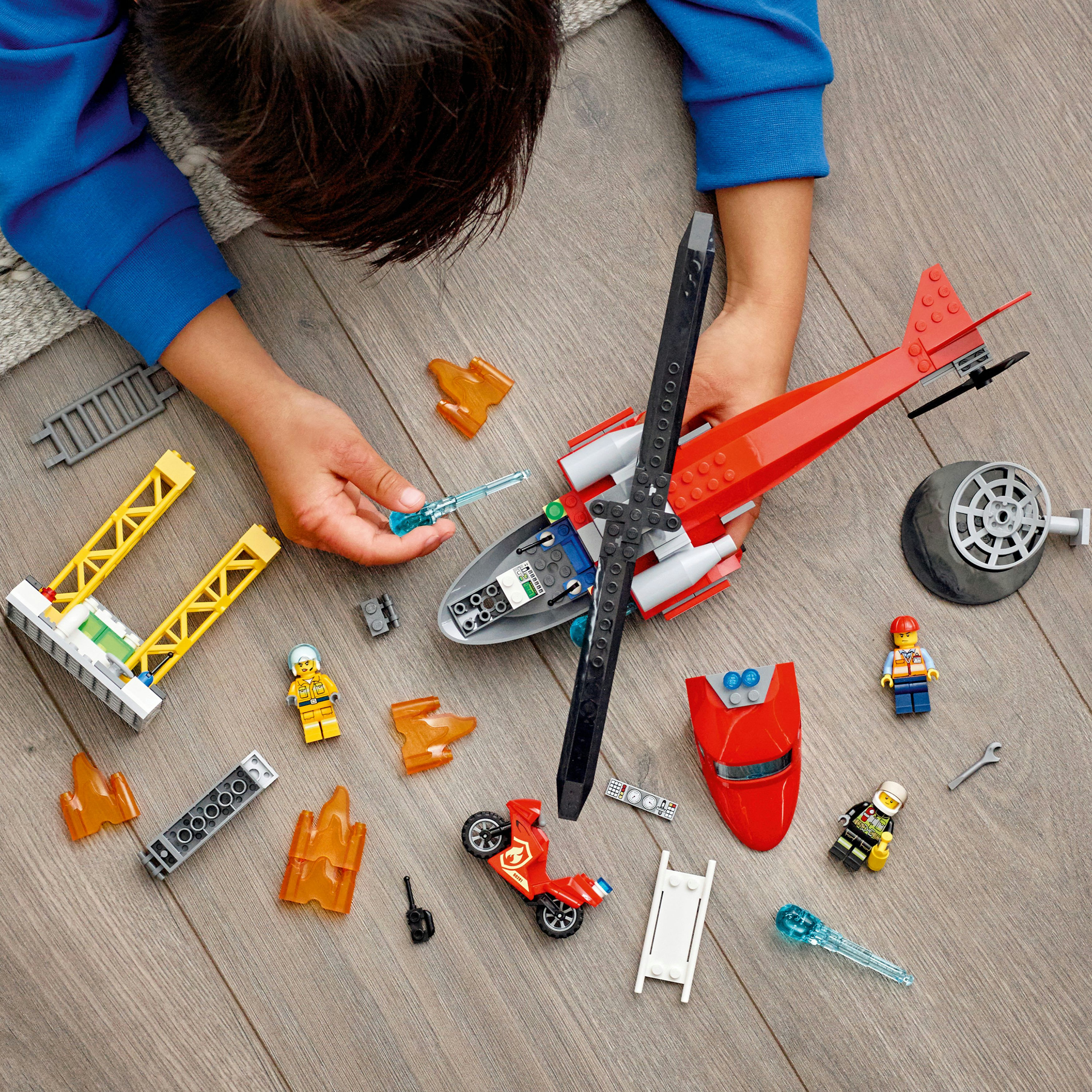 Ein Kind, das ein Lego City Hubschrauber-Set mit Figuren und Teilen zusammenbaut.