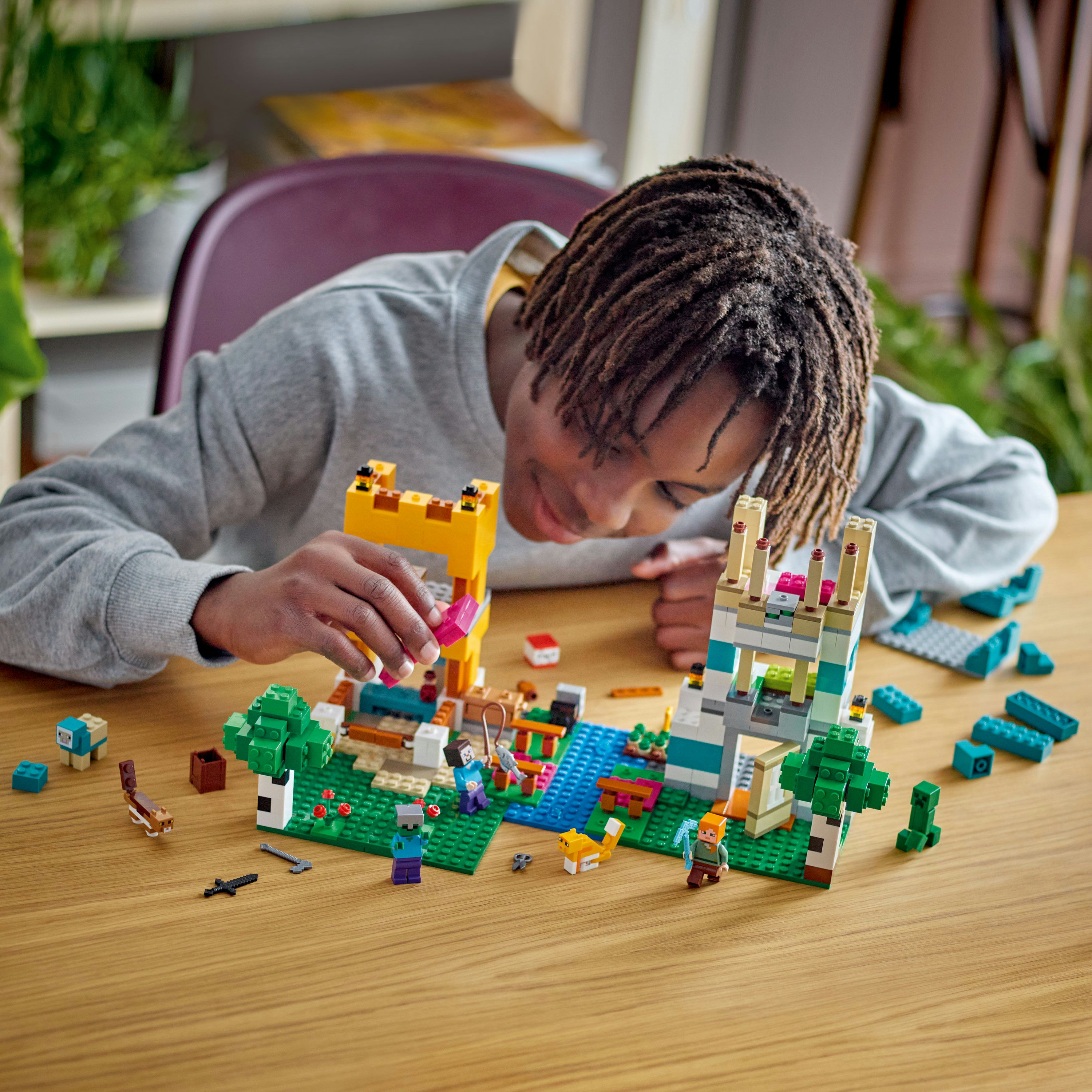 Eine Person baut eine LEGO Minecraft Szene. Enthält eine Brücke, Bäume und verschiedene Charaktere.