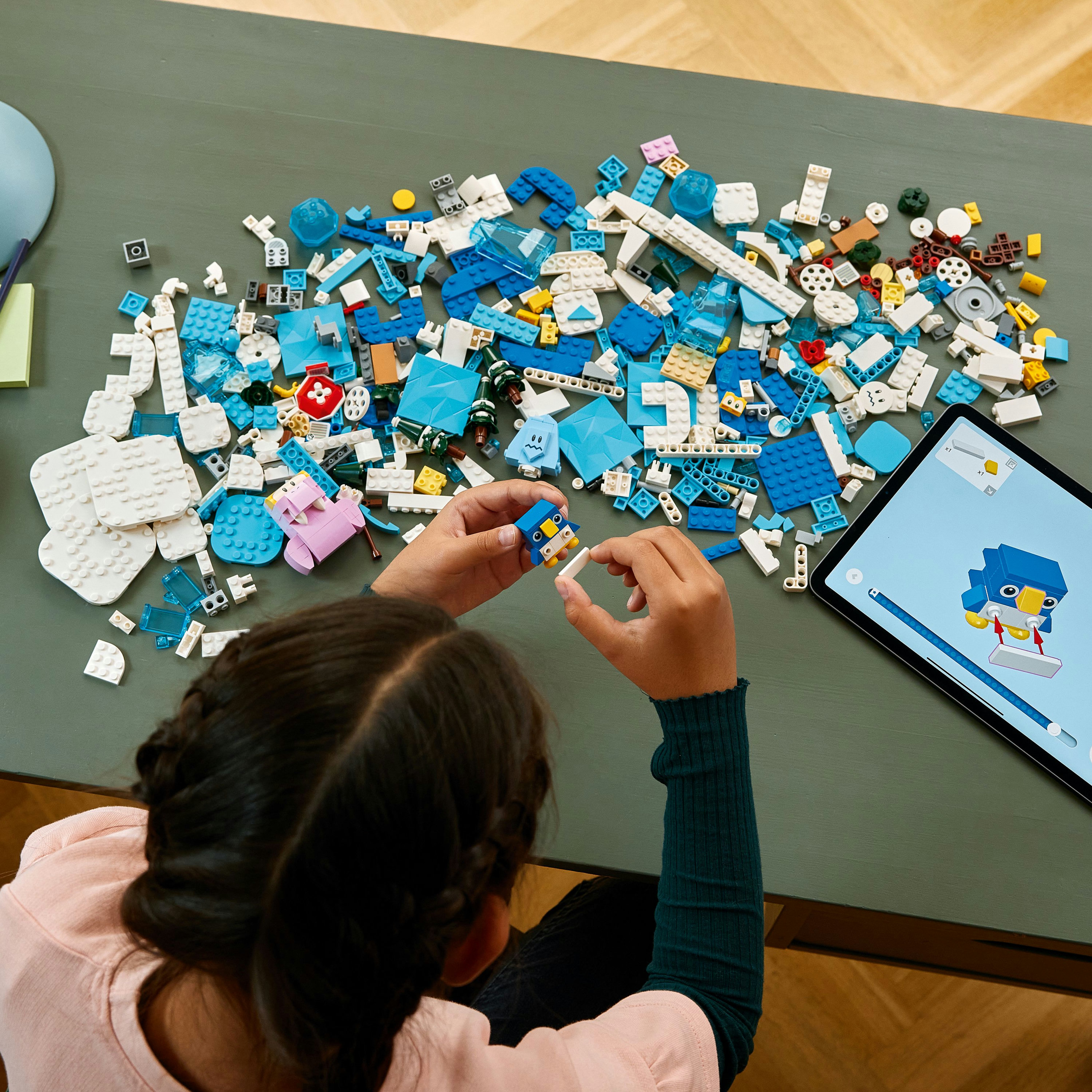 Kind dat Lego-stukken in elkaar zet. Een blauw-witte Lego set op een grijs oppervlak.