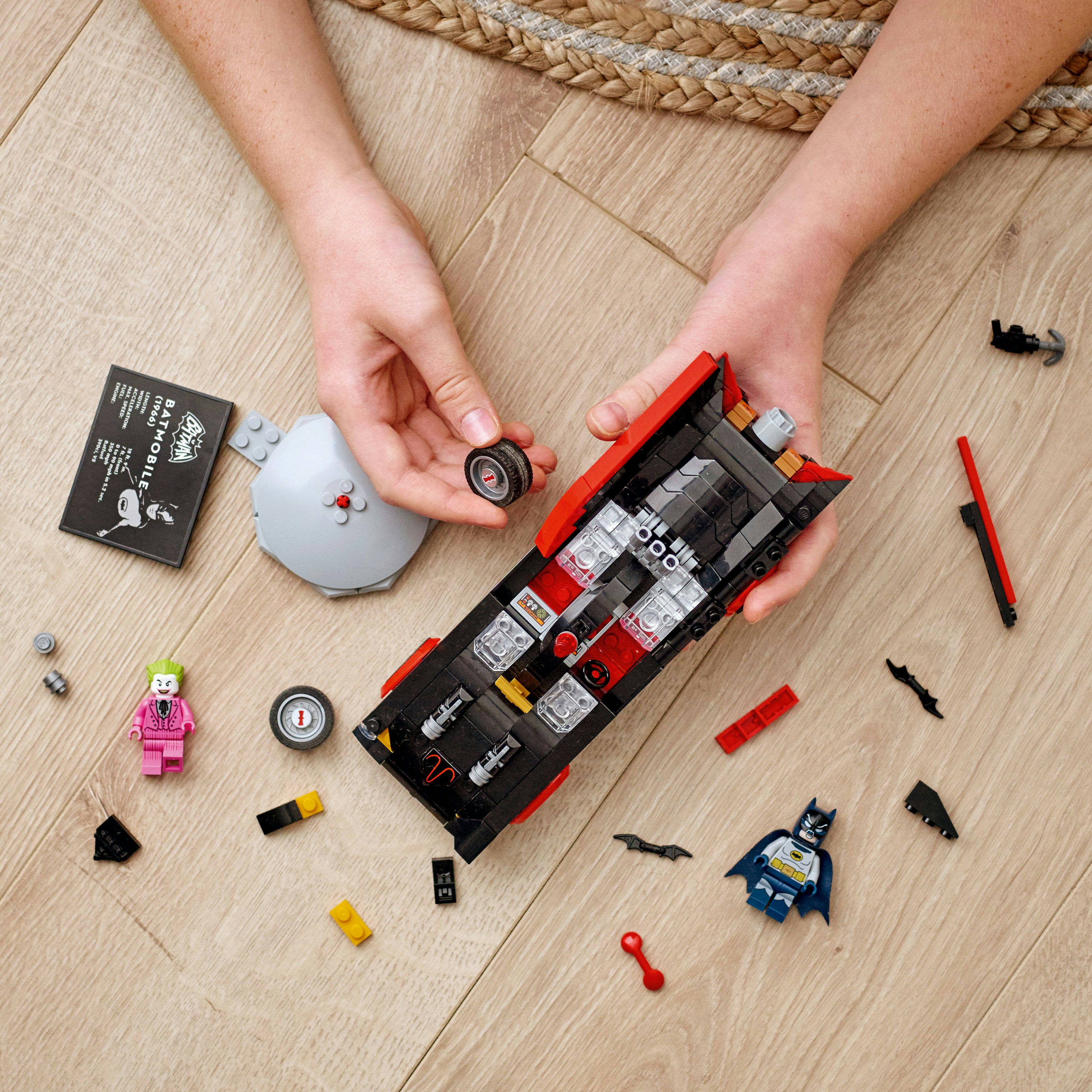 Yapım aşamasında Lego Batmobile. Ahşap bir yüzeyde mini figürler ve bileşenler.