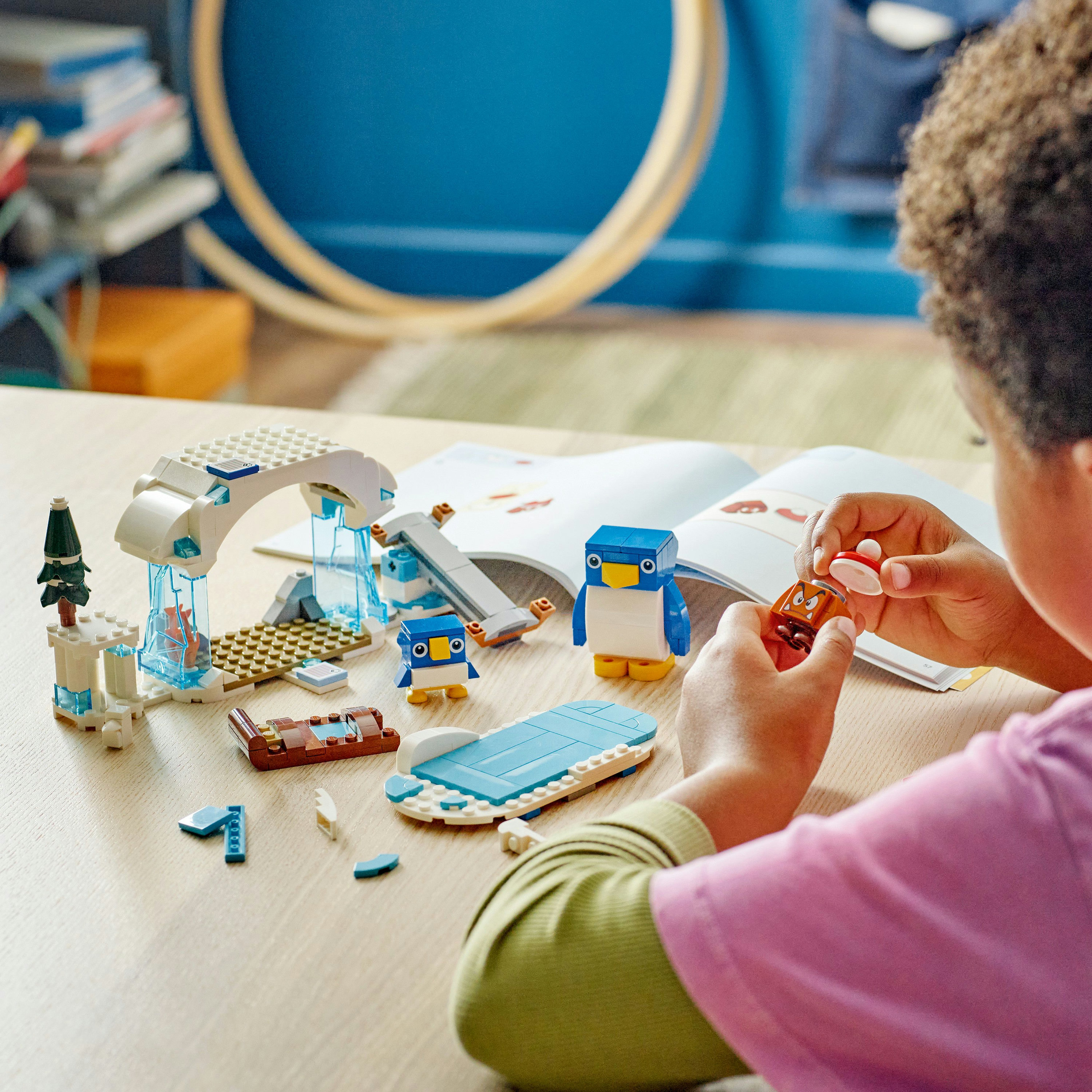 Un niño ensamblando un set de Lego con pingüinos, un iglú y otros elementos de una escena ártica.
