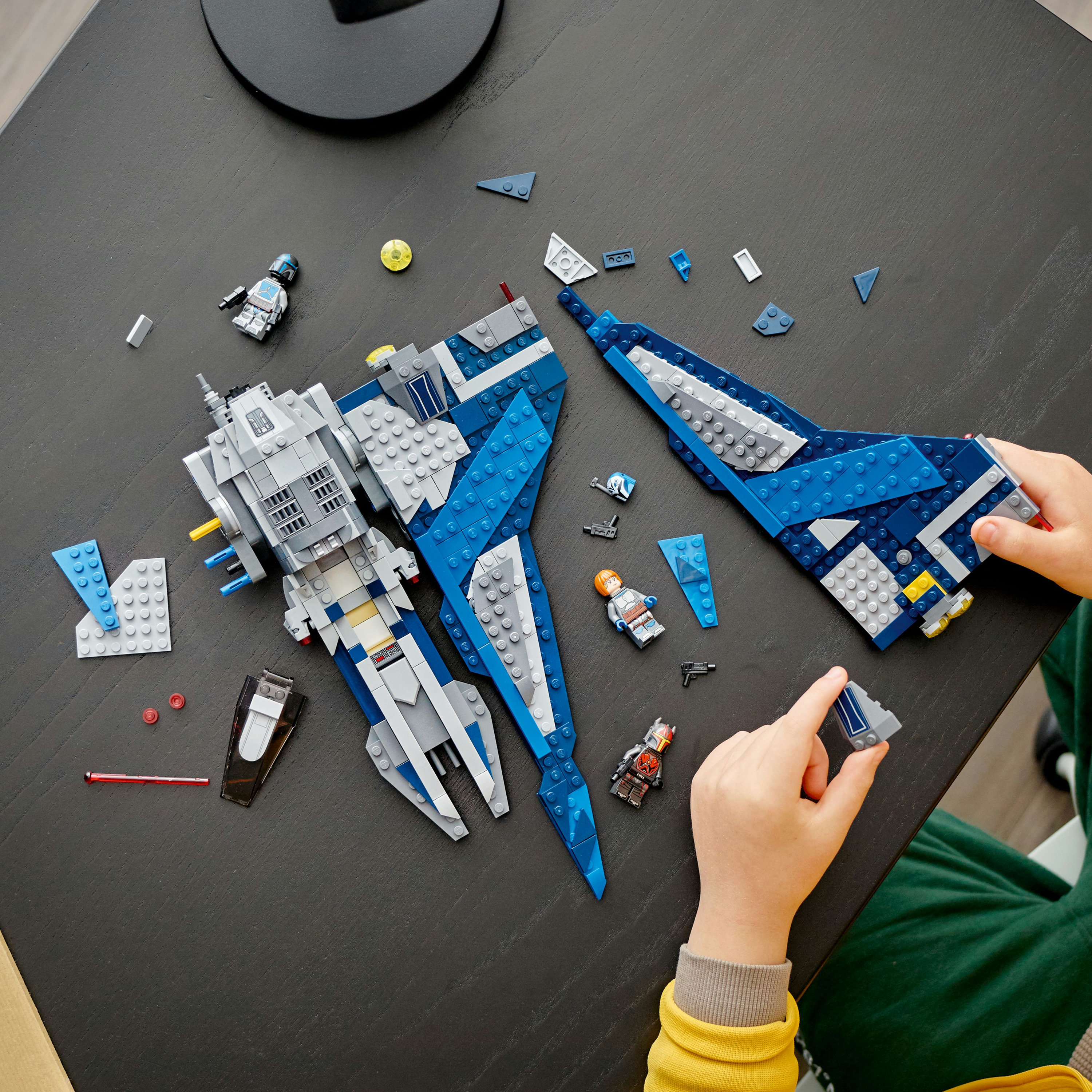 Set Lego Star Wars in costruzione su un tavolo nero, mani di bambino.