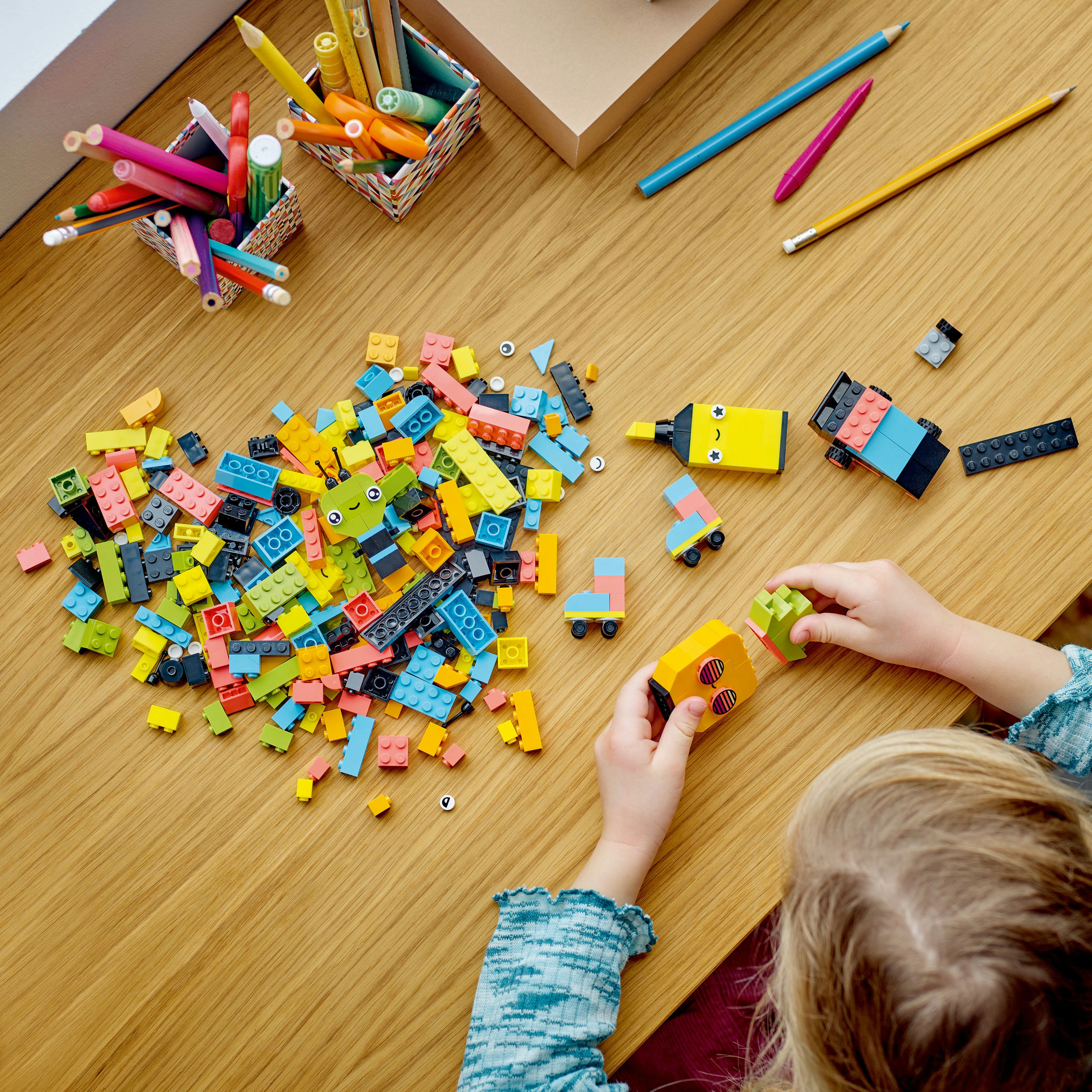 Een kind bouwt met kleurrijke Lego-stenen op een houten tafel.