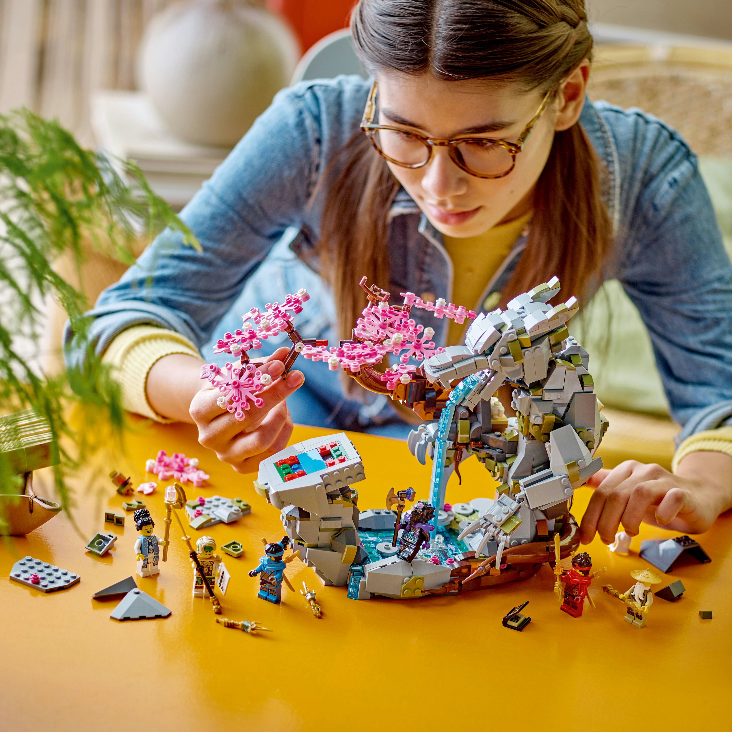 Ein Mädchen baut ein LEGO Ninjago Set, eine Felsstruktur mit Wasserfall und Figuren.