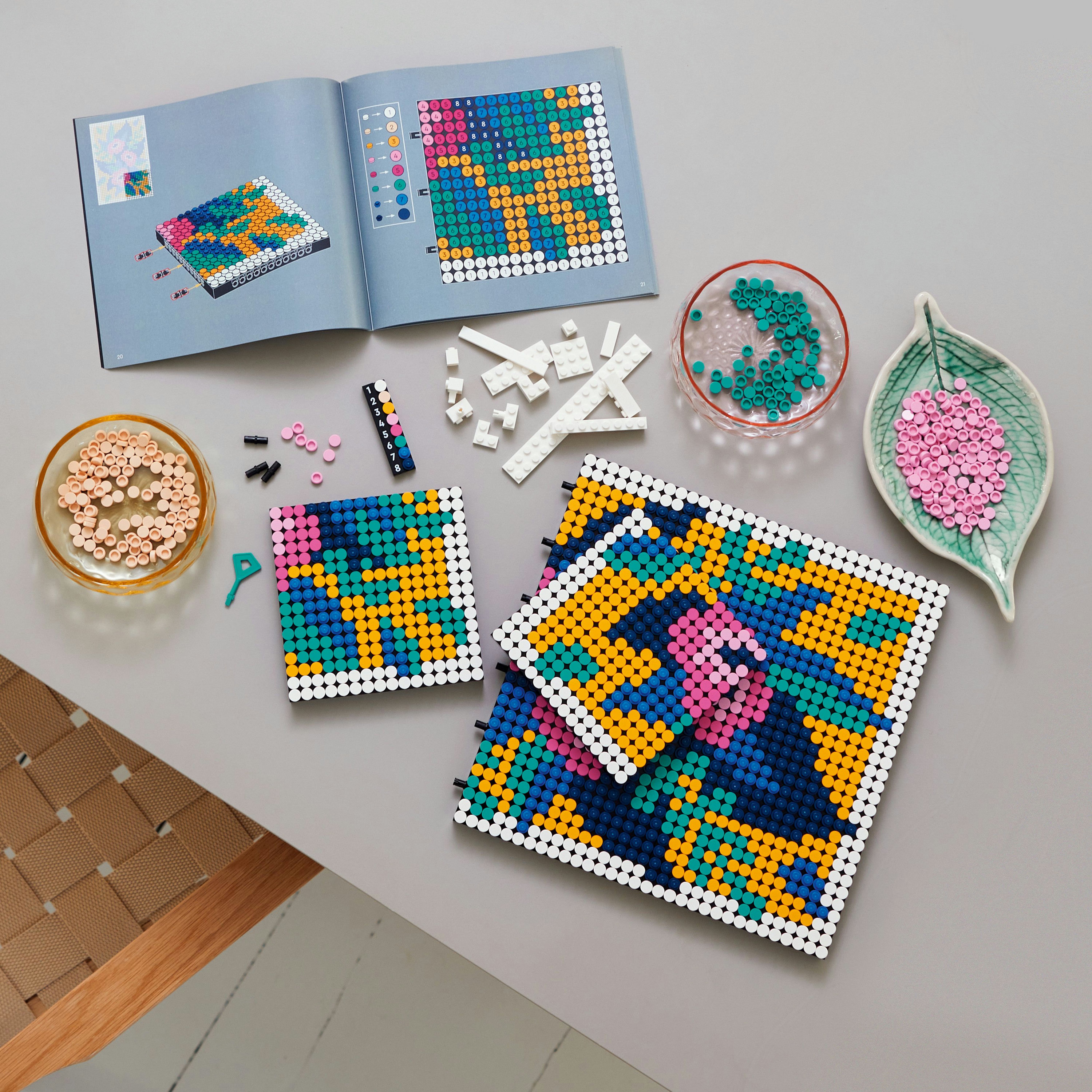 Un set de arte Lego con múltiples baldosas de color y un folleto. Hay 3 obras de arte terminadas.