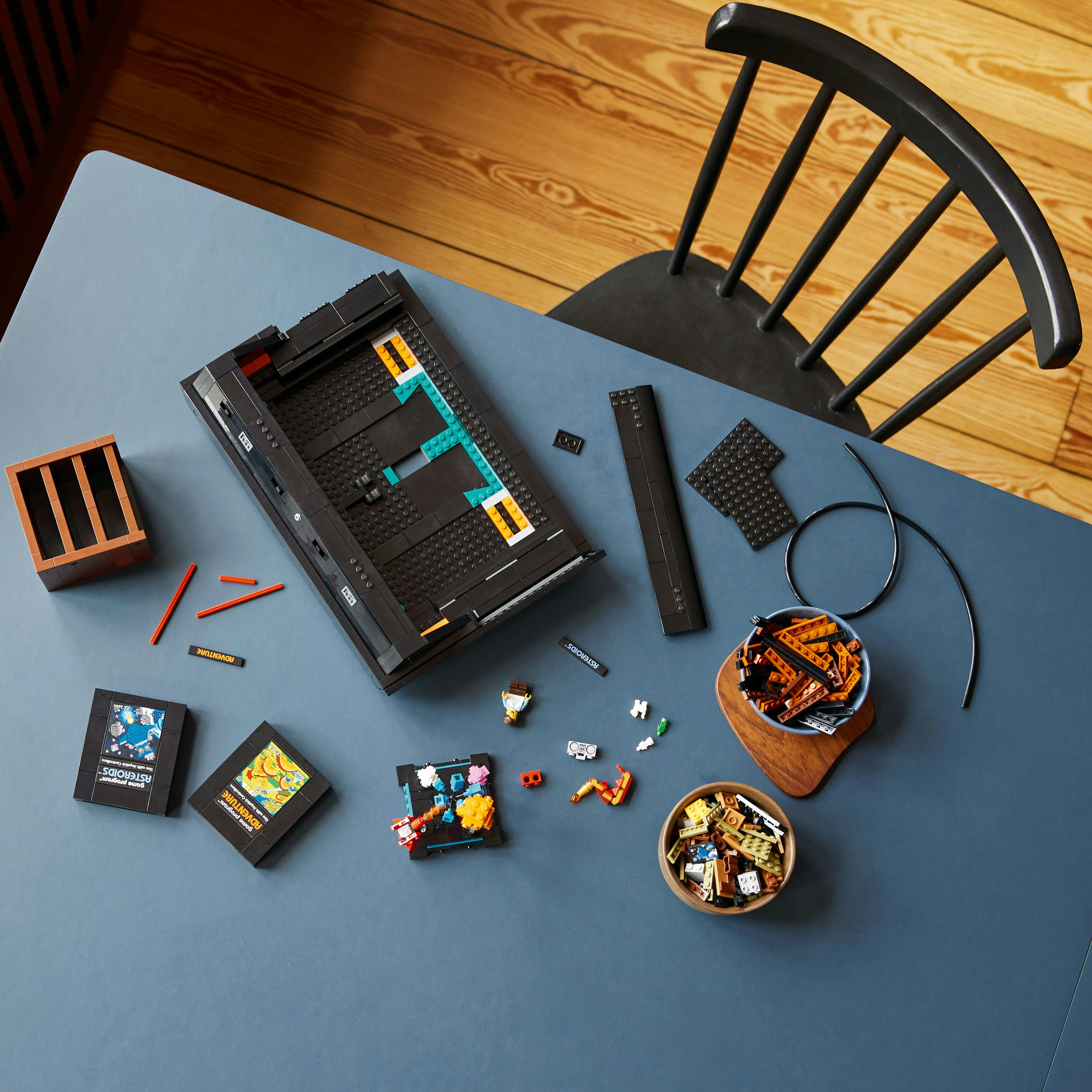 Draufsicht auf Lego-Steine und Zubehör auf einem blauen Tisch, darunter eine schwarze Tafel und Schalen.