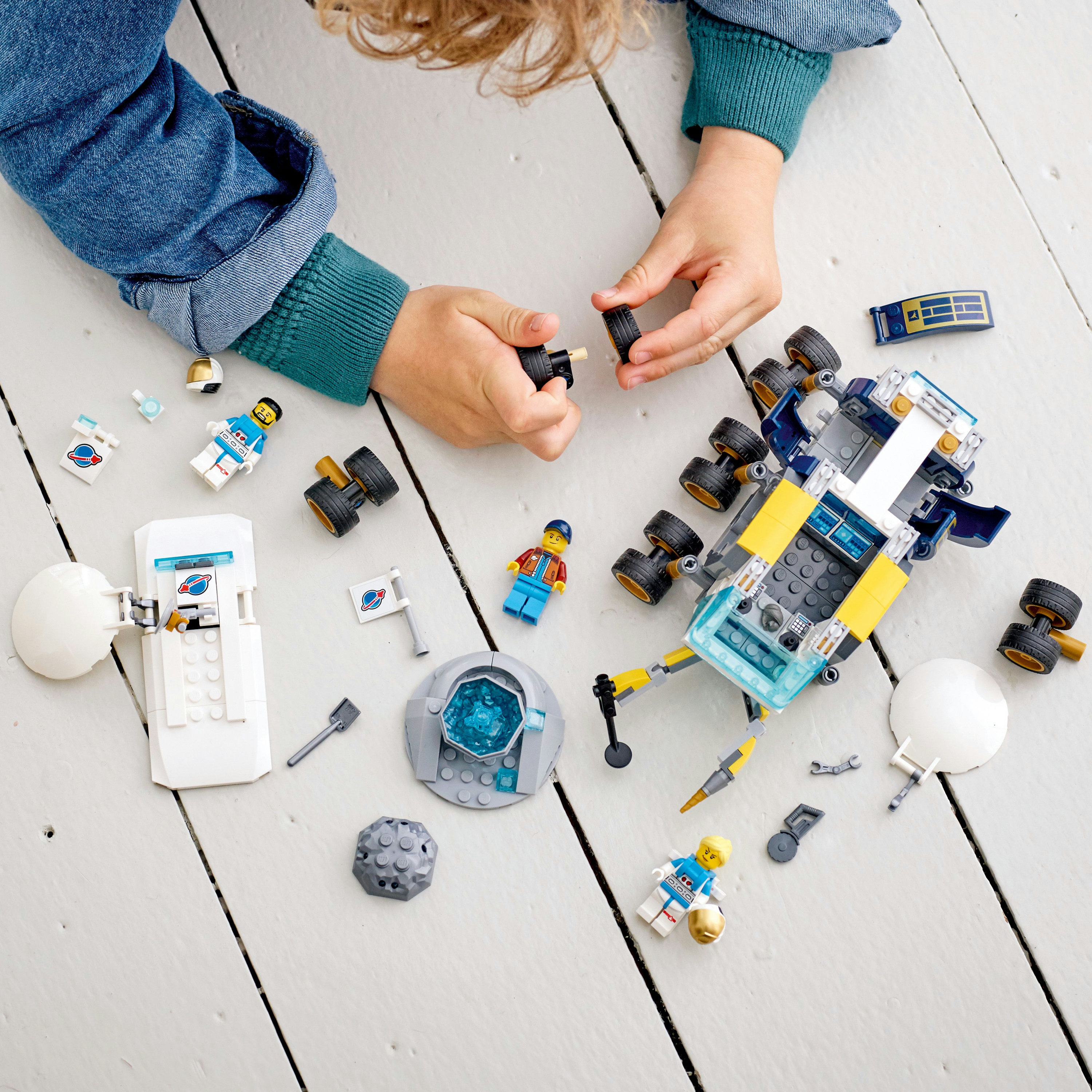 Ein Kind spielt mit einem Lego Weltraum-Set, einschließlich Figuren, einer Mondlandefähre und verstreuten Teilen.