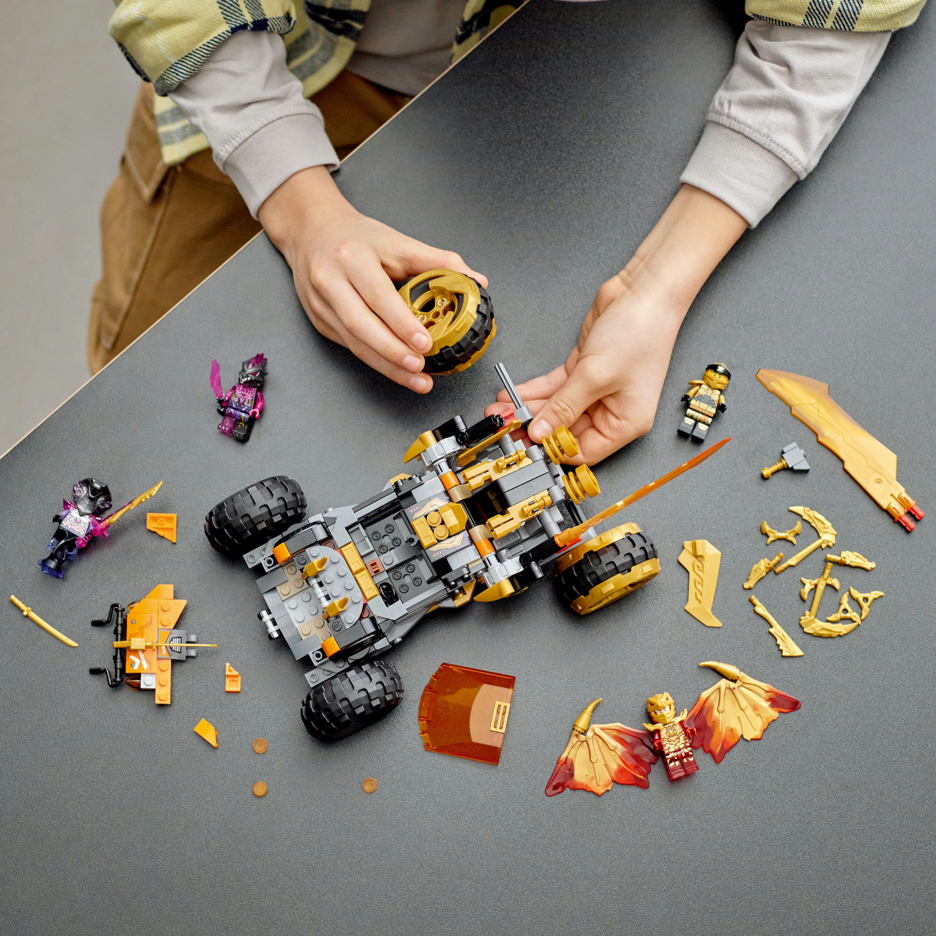 Ein Lego Ninjago Set wird von Händen gebaut. Ein grauer Tisch mit verstreuten Komponenten.