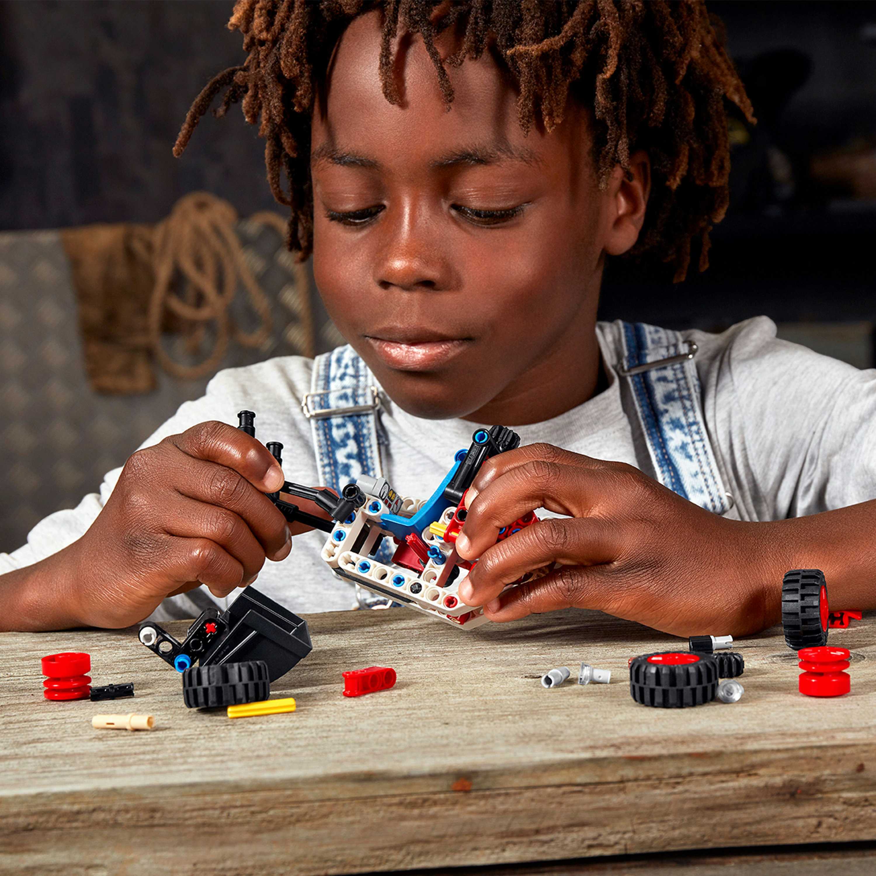 Ein junger Junge baut mit Lego-Steinen. Er konzentriert sich auf den Zusammenbau eines kleinen, bunten Modells.
