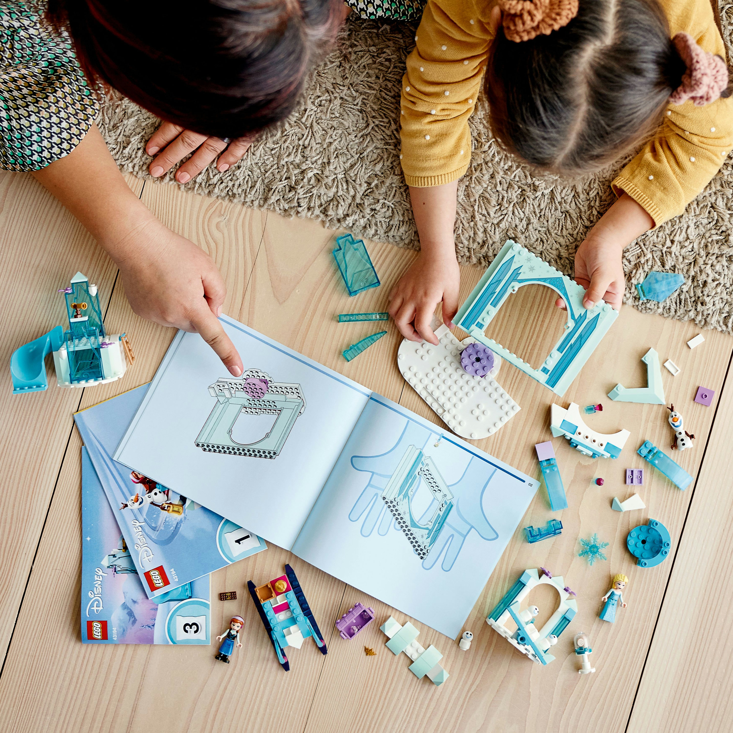 Zwei Personen, ein Erwachsener und ein Kind, spielen mit Lego-Bausteinen eines Gebäudes.