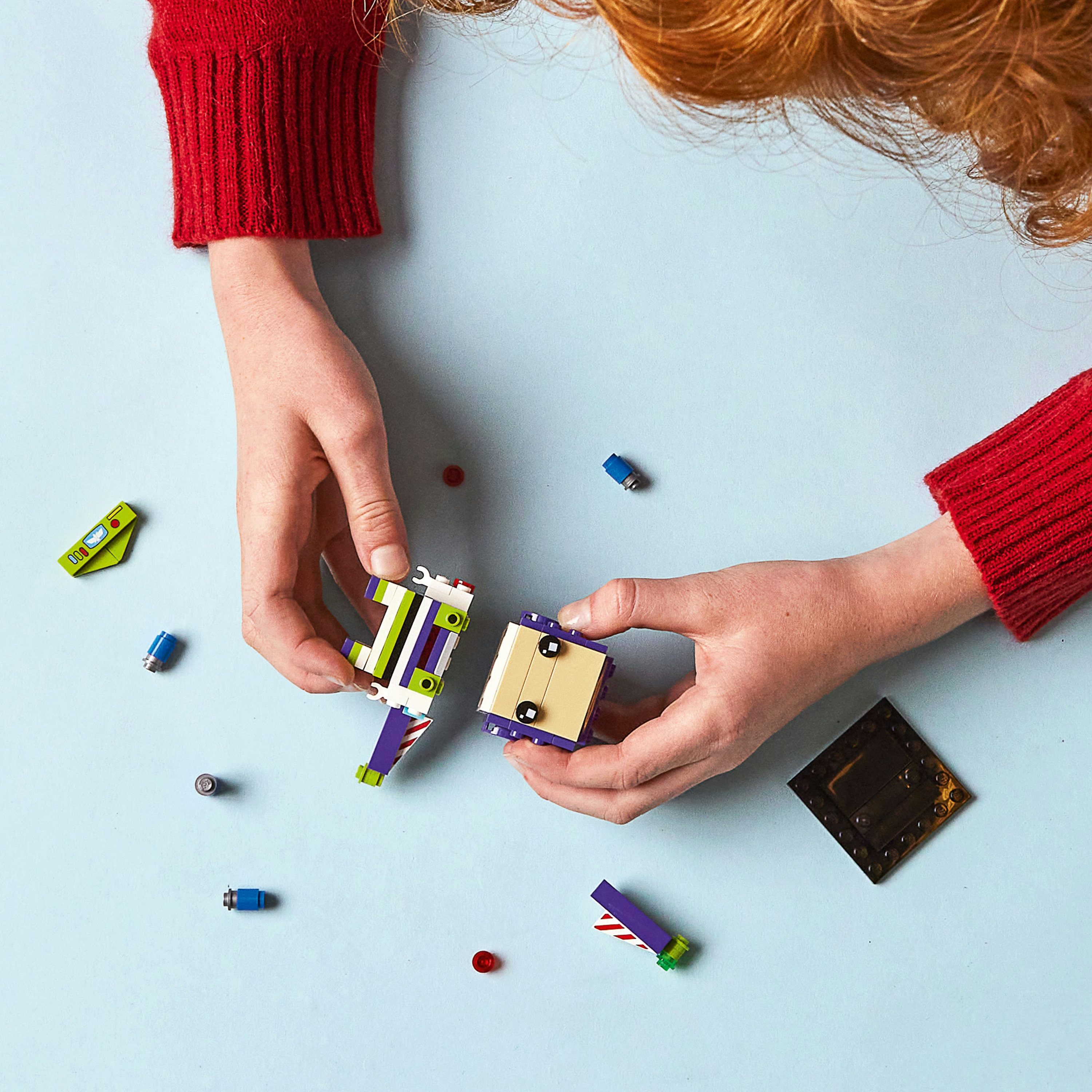 Eller Lego parçalarını birleştiriyor: yeşil, mor ve sarı bloklar. Mavi arka plan.
