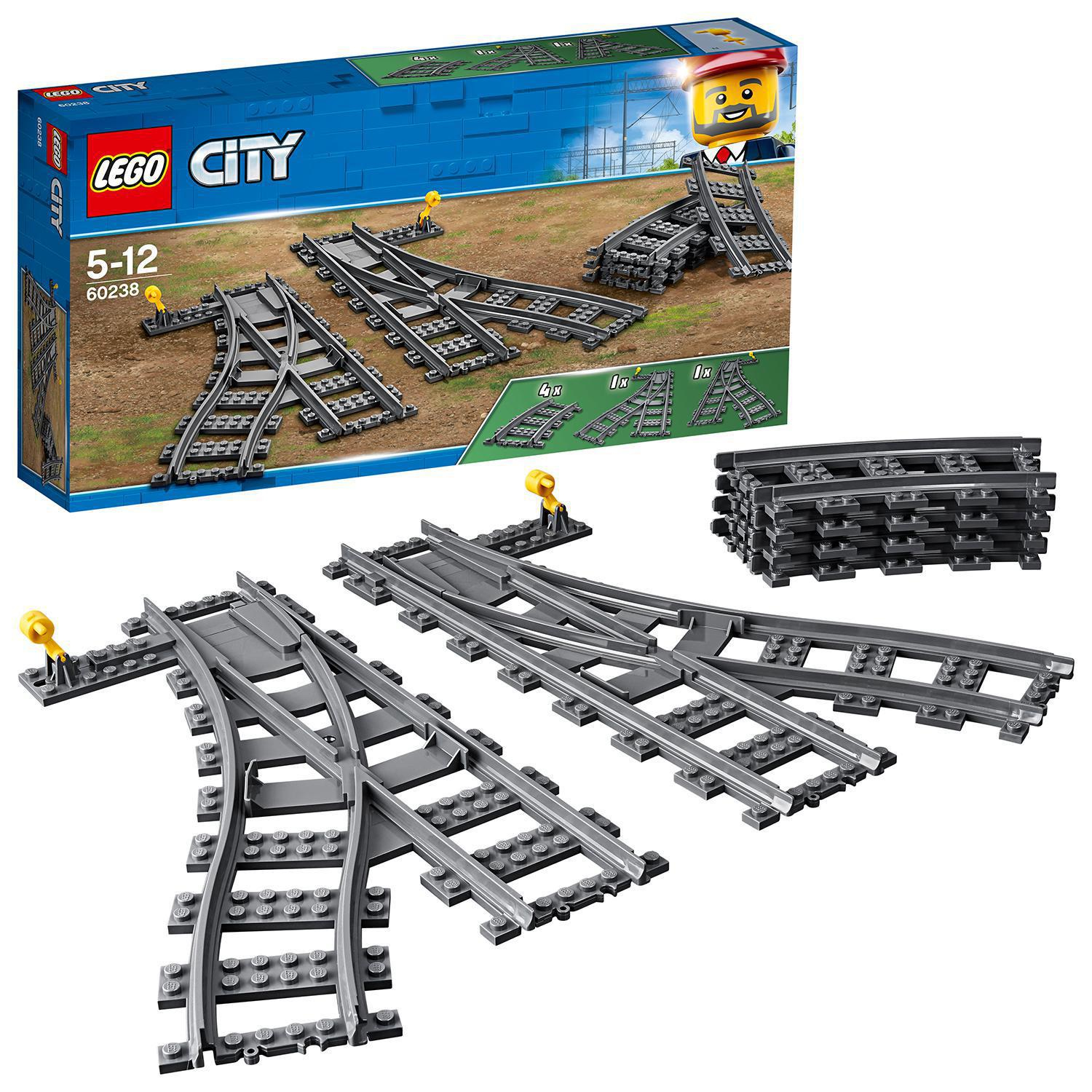 Zestaw torów kolejowych LEGO City z różnymi zakrętami i zwrotnicami oraz pudełkiem.