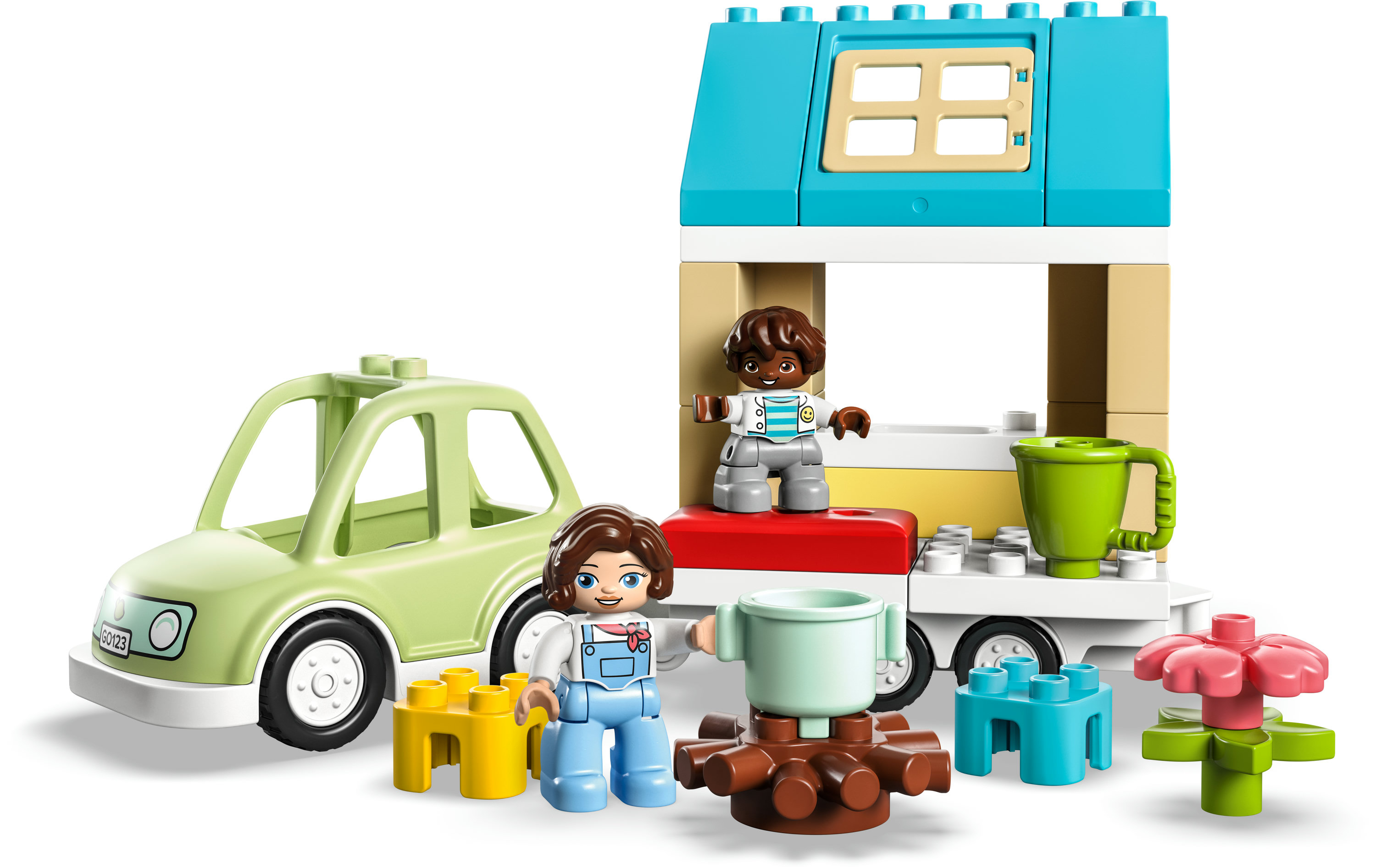Lego Duplo Szene mit einem Auto, zwei Figuren, einem Haus und Zubehör wie Tassen und einer Blume.