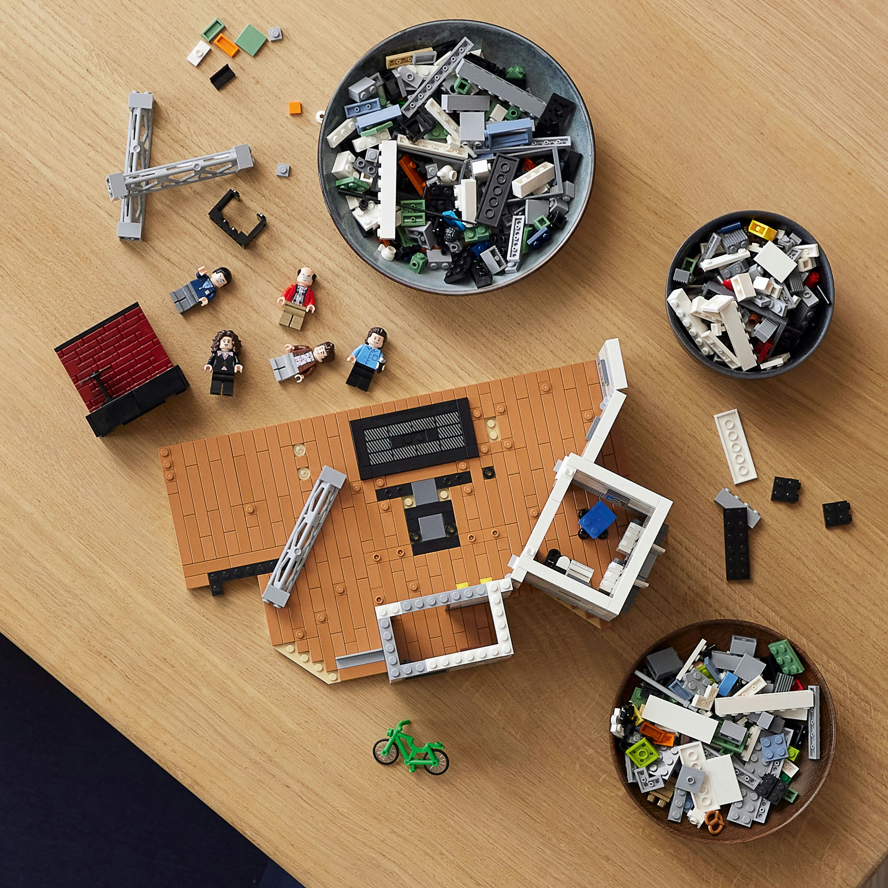 Lego Titanic Modellteile verstreut auf einem Holztisch mit drei Schalen voller Steine.