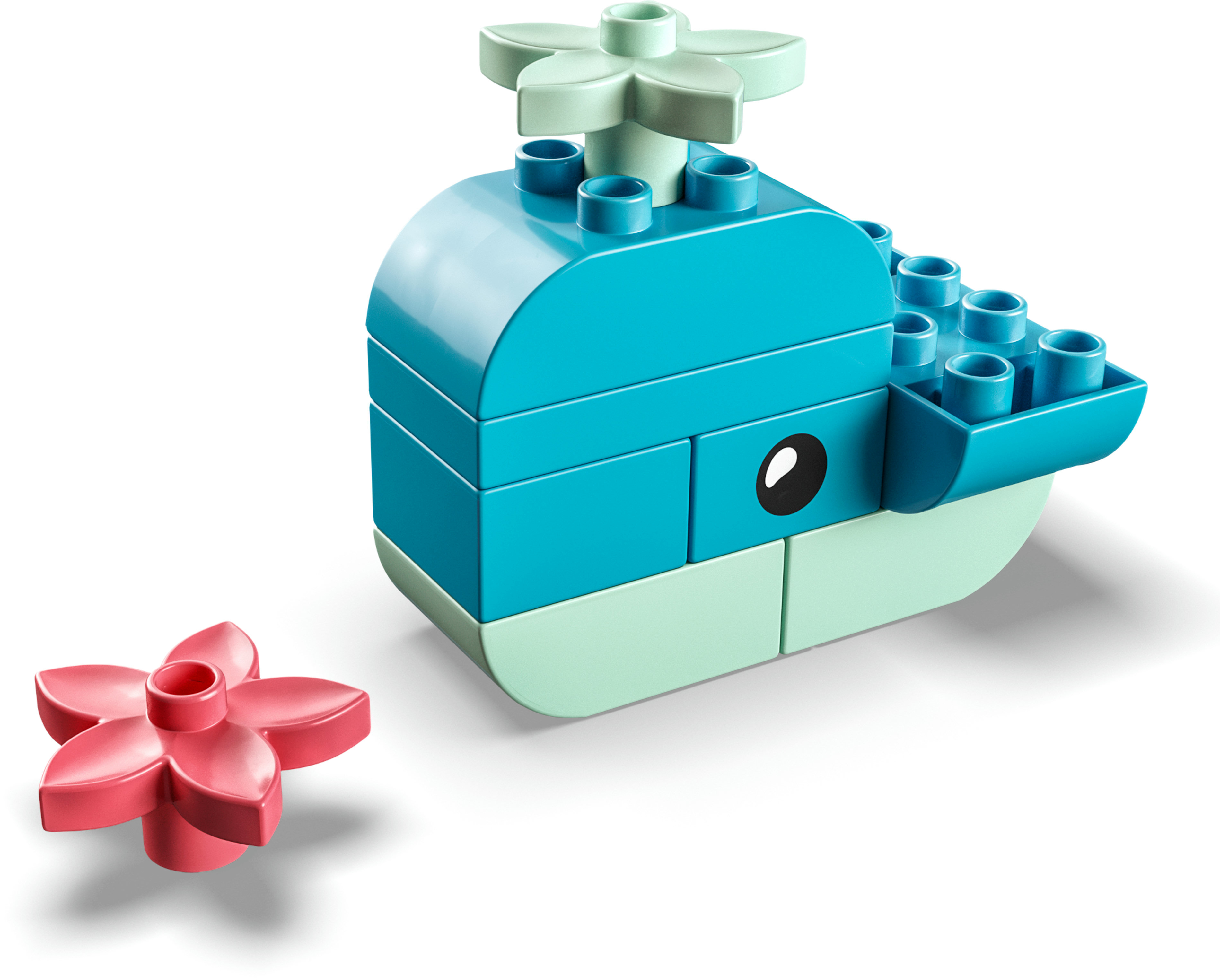 Een walvis gemaakt van blauwe en mintgroene Lego-blokken met een roze bloem.