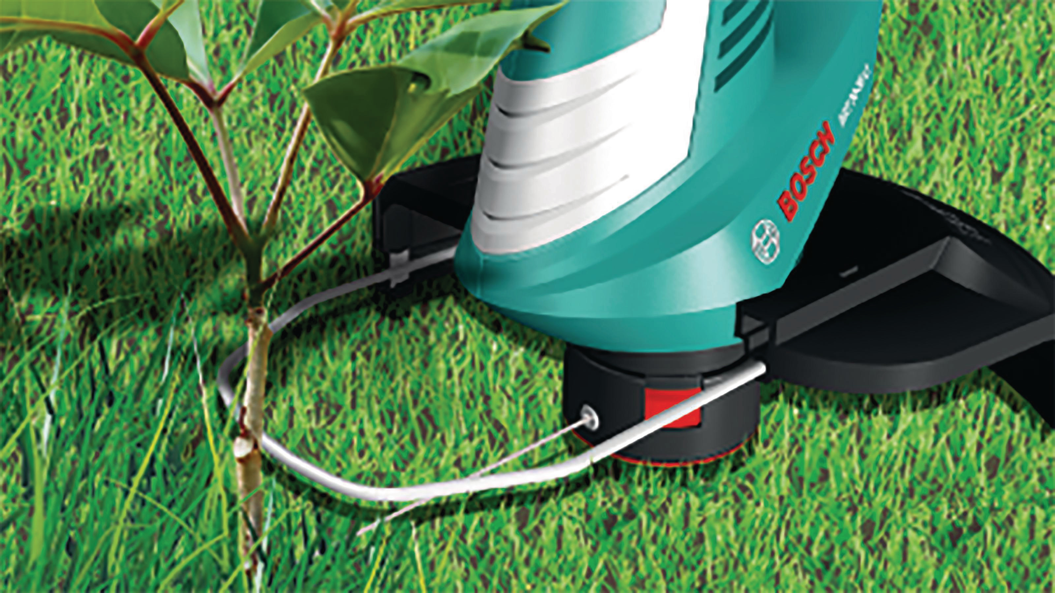 Un recortador de césped BOSCH recorta cerca de un árbol pequeño. Se ve hierba verde y un cable blanco.