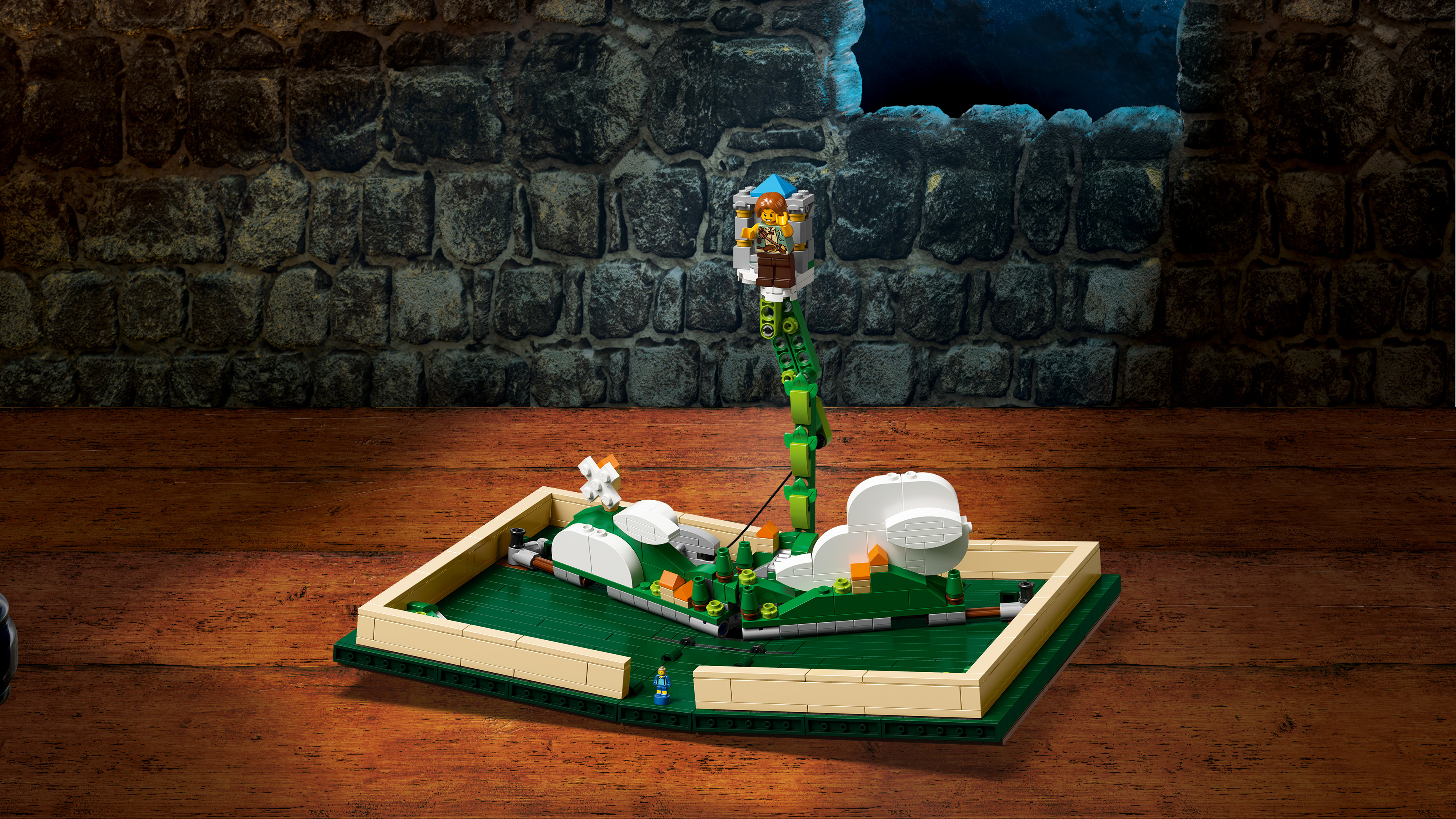 Scena z bajki Lego w otwartej książce. Widoczna jest wieża z ludźmi i zielonym pnączem.