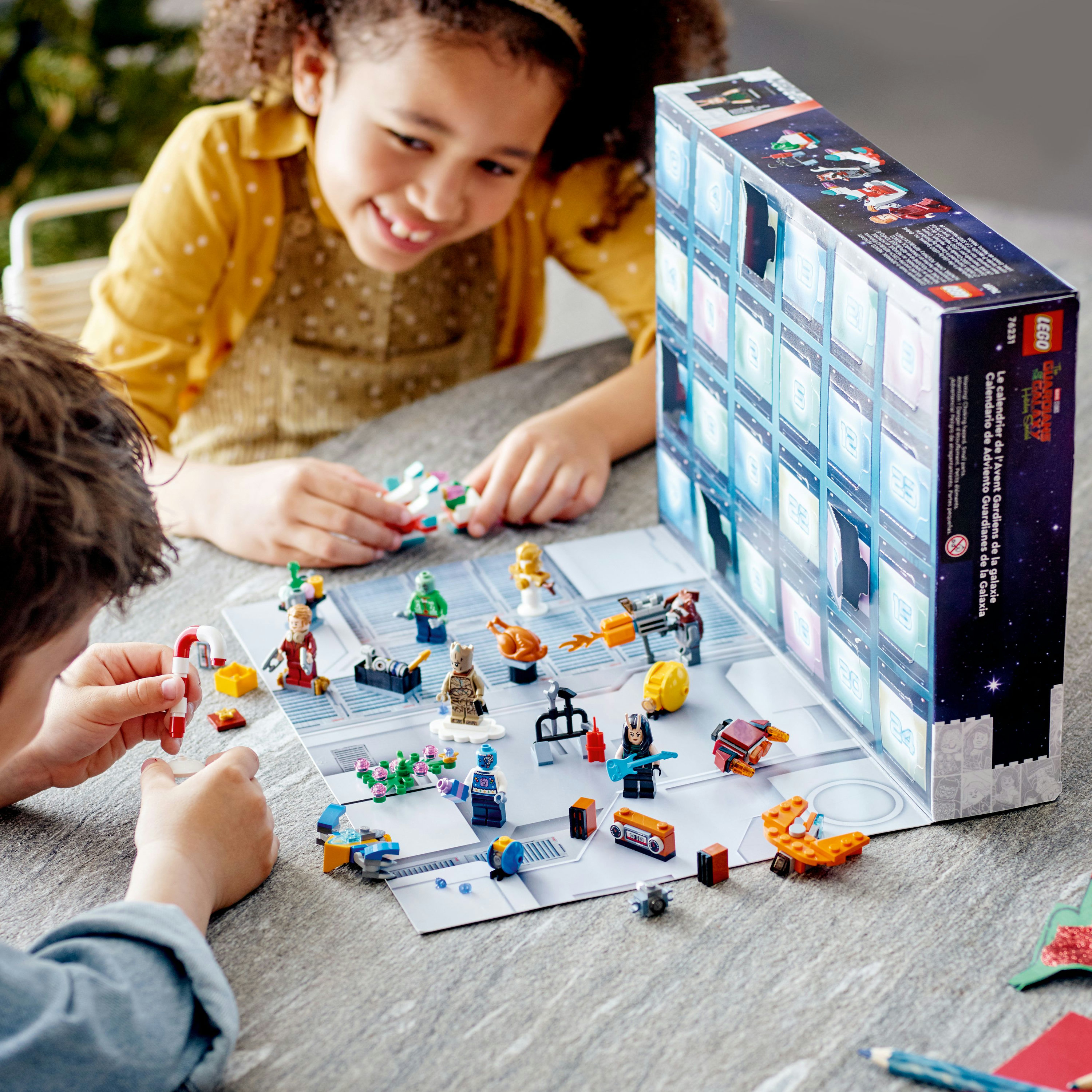 Kinder bauen Lego-Figuren zusammen. Lego-Box im Hintergrund.
